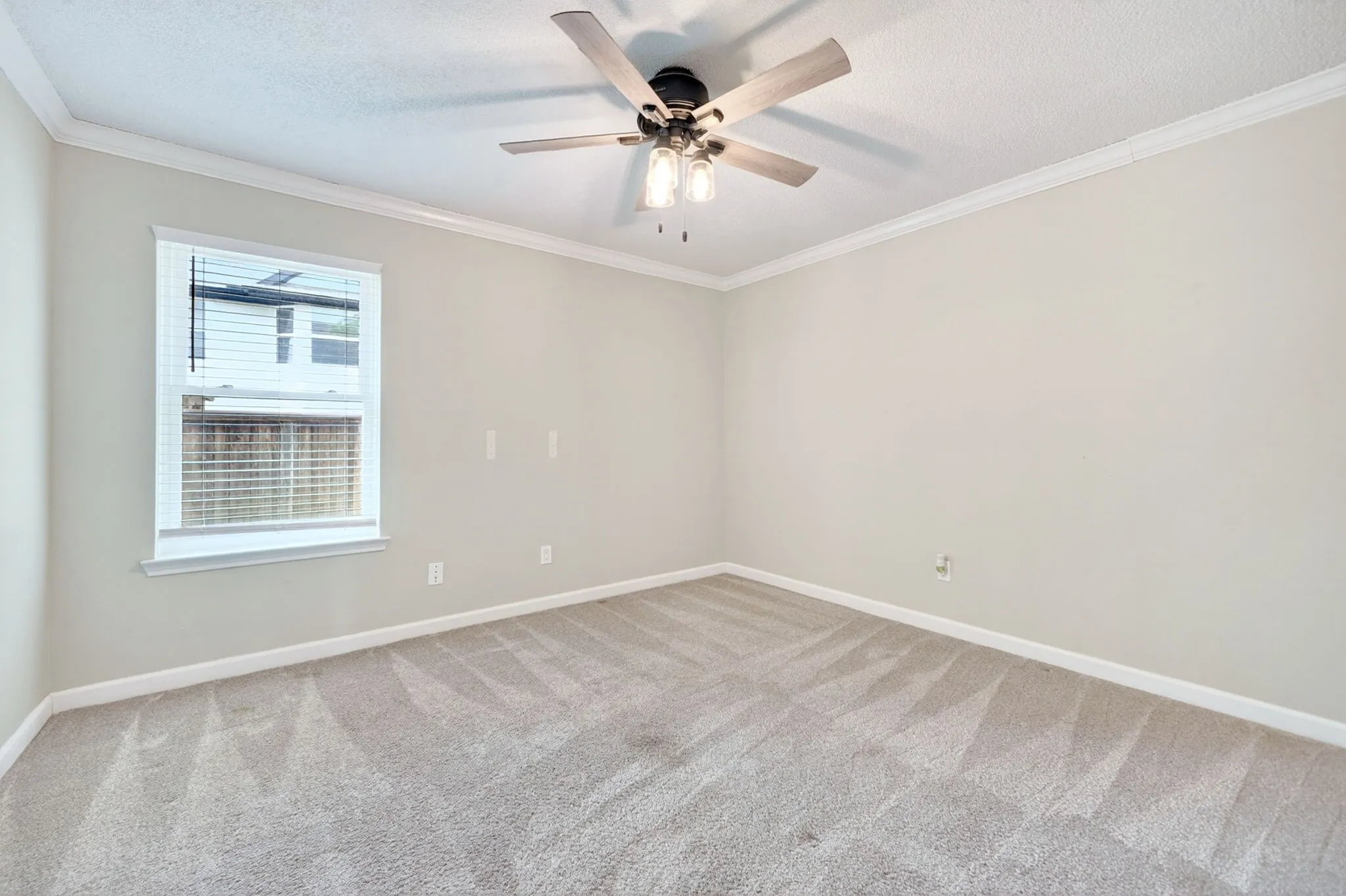 Neutral wall color, crown molding, ceiling fan with integrated lighting, window with blinds, and patterned carpet
