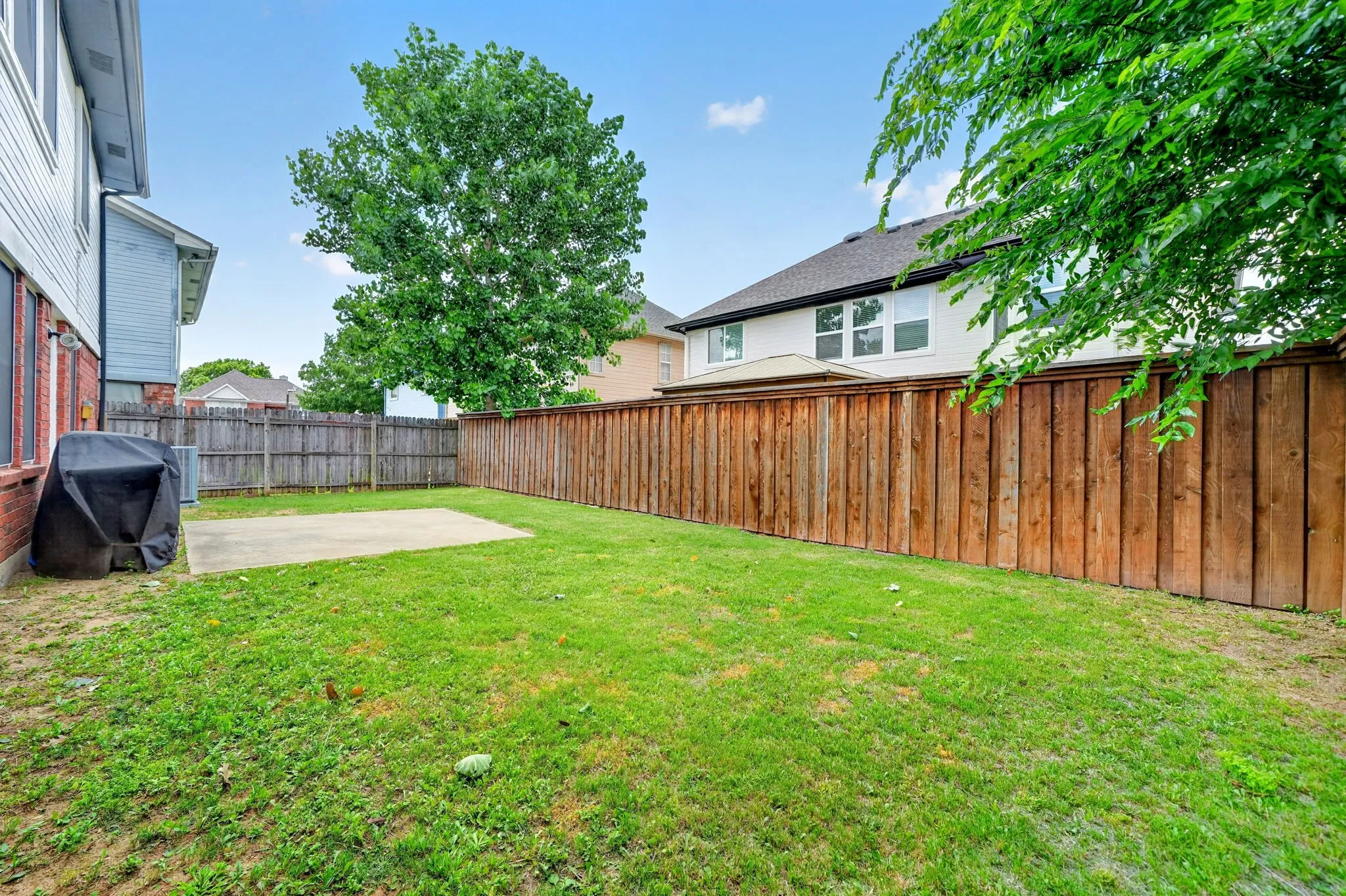 Expansive backyard featuring a lush lawn, concrete patio, and privacy fencing