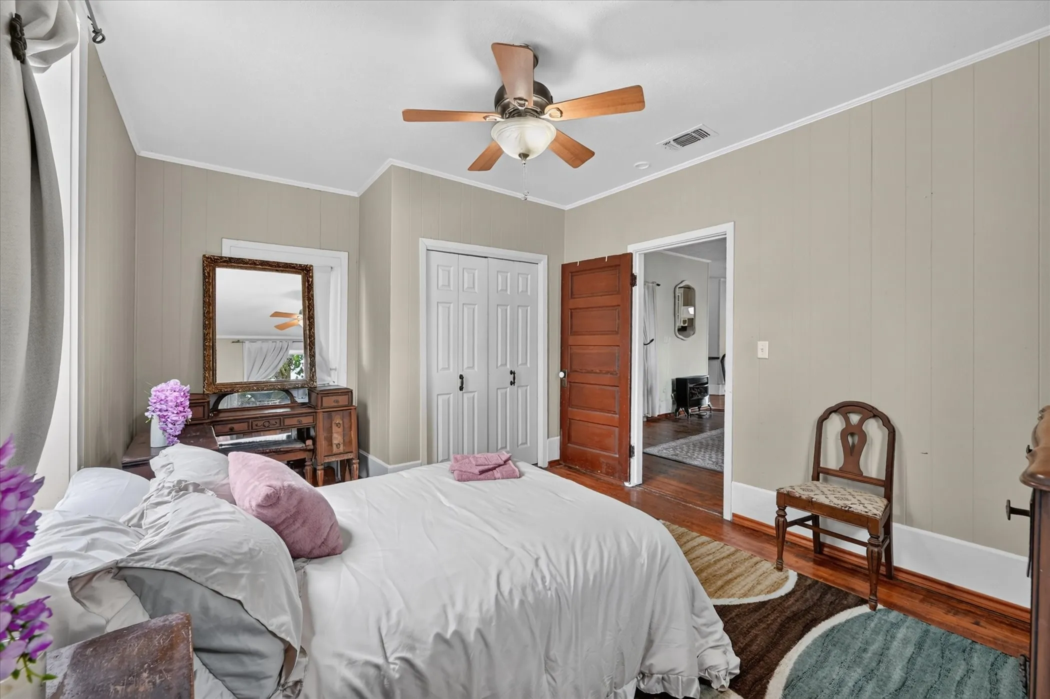 Wood-finish flooring, paneled wall detailing, ceiling fan with light fixture, and white bi-fold closet doors