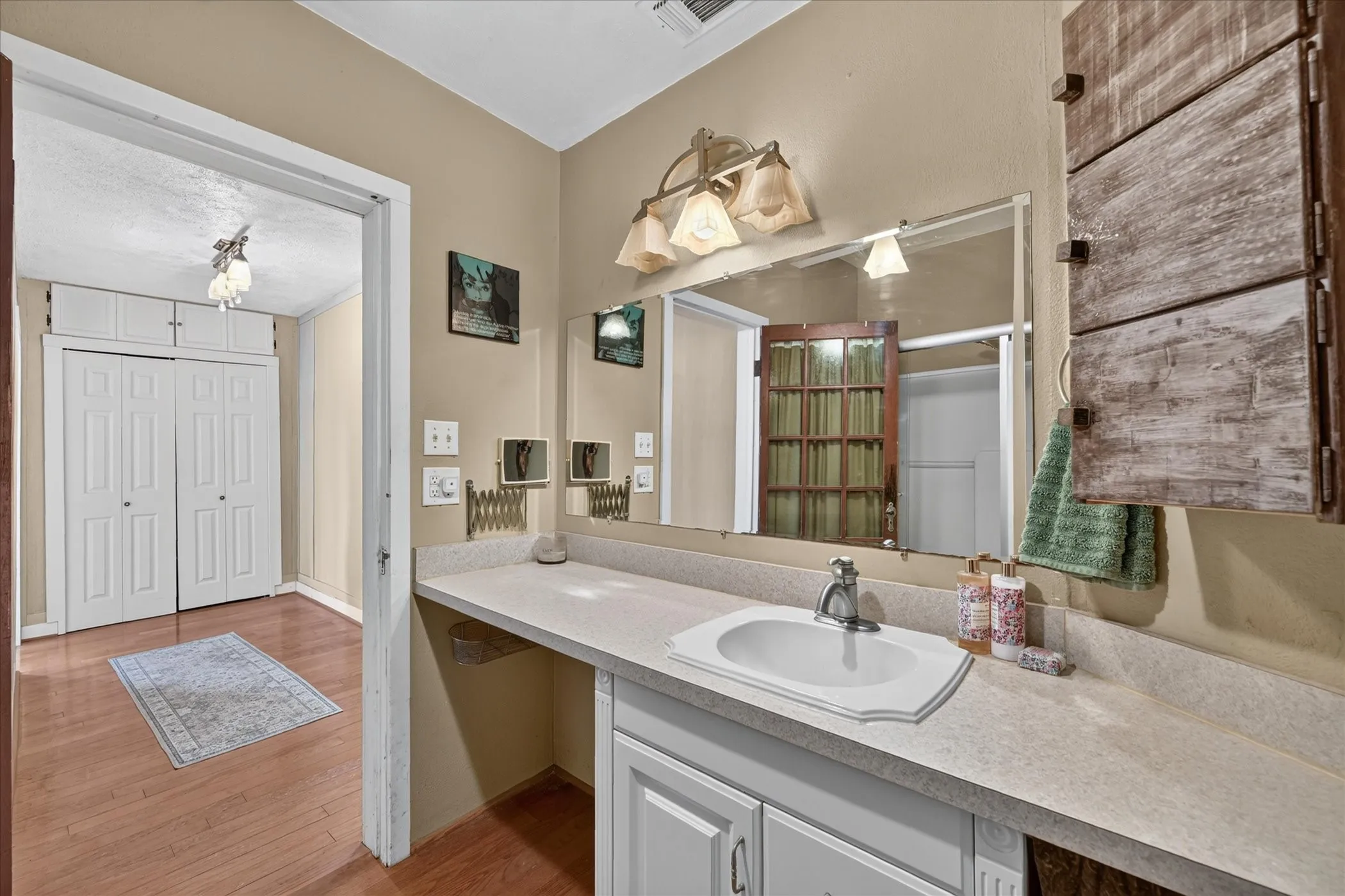 Vanity with integrated sink, expansive countertop, and wall-mounted mirror