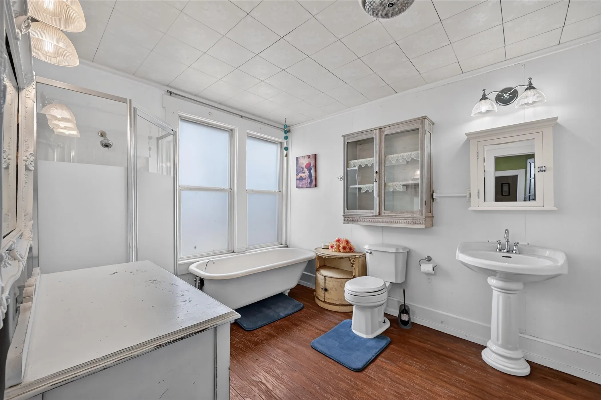Pedestal sink with chrome fixtures, a clawfoot tub, and a separate shower enclosure