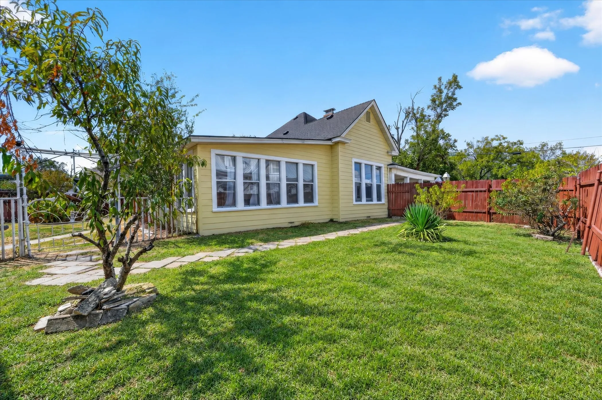 Yellow siding exterior with white trim windows and a dark shingle roof
