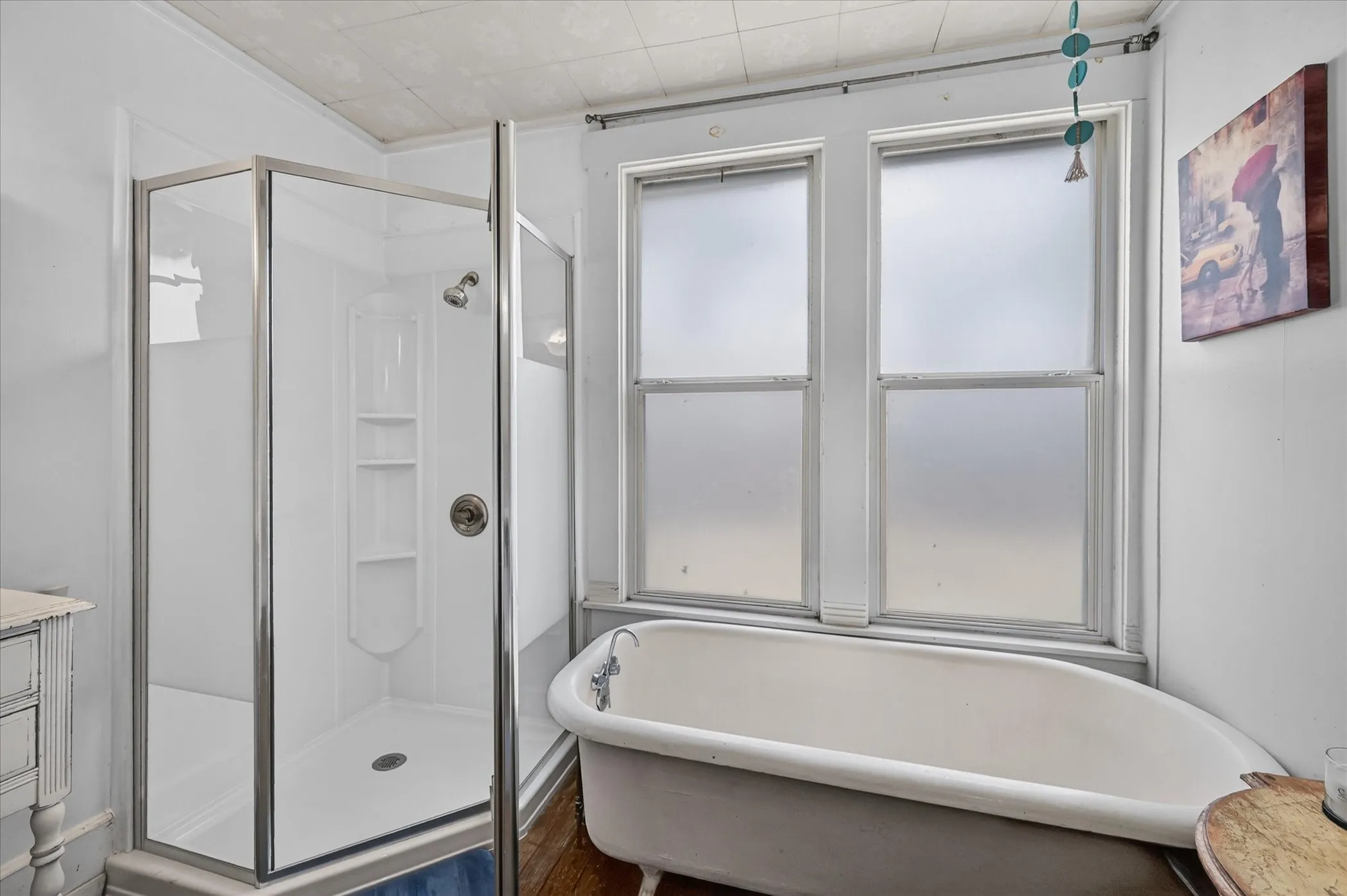 Walk-in shower with integrated shelving, freestanding clawfoot bathtub, and double-hung windows