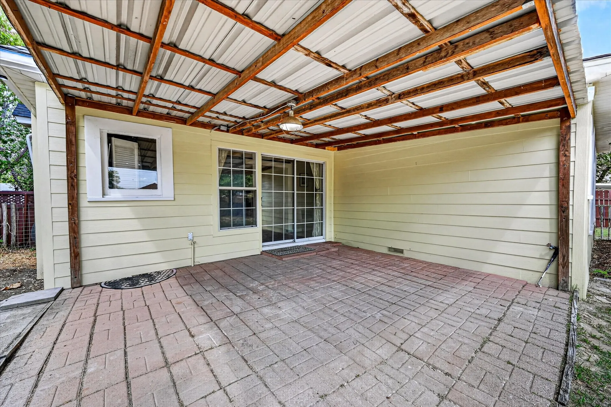 Covered patio featuring a brick paver surface, horizontal siding, and a sliding glass door
