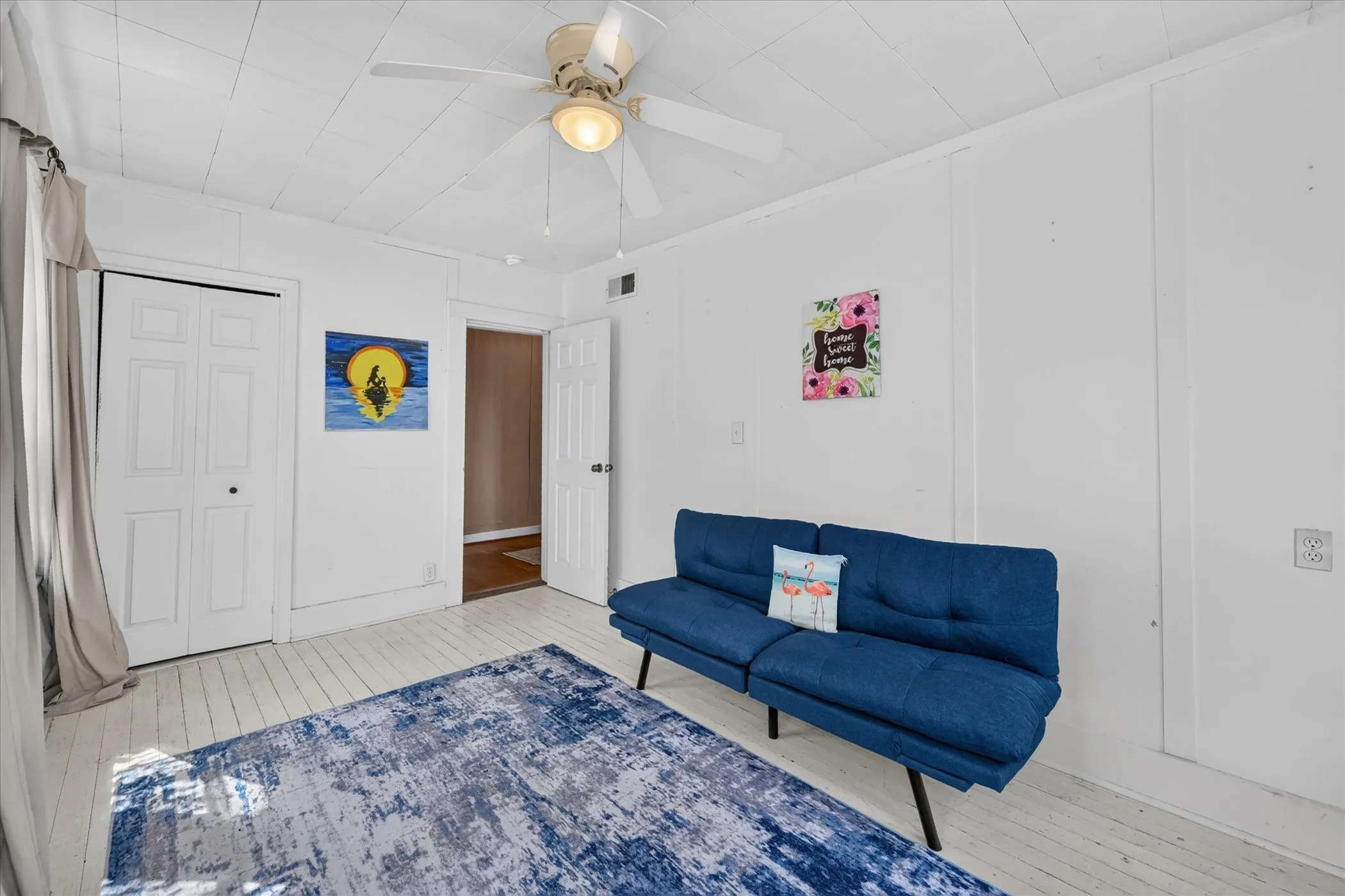 White plank flooring, paneling walls, ceiling fan with integrated lighting, and bi-fold closet doors