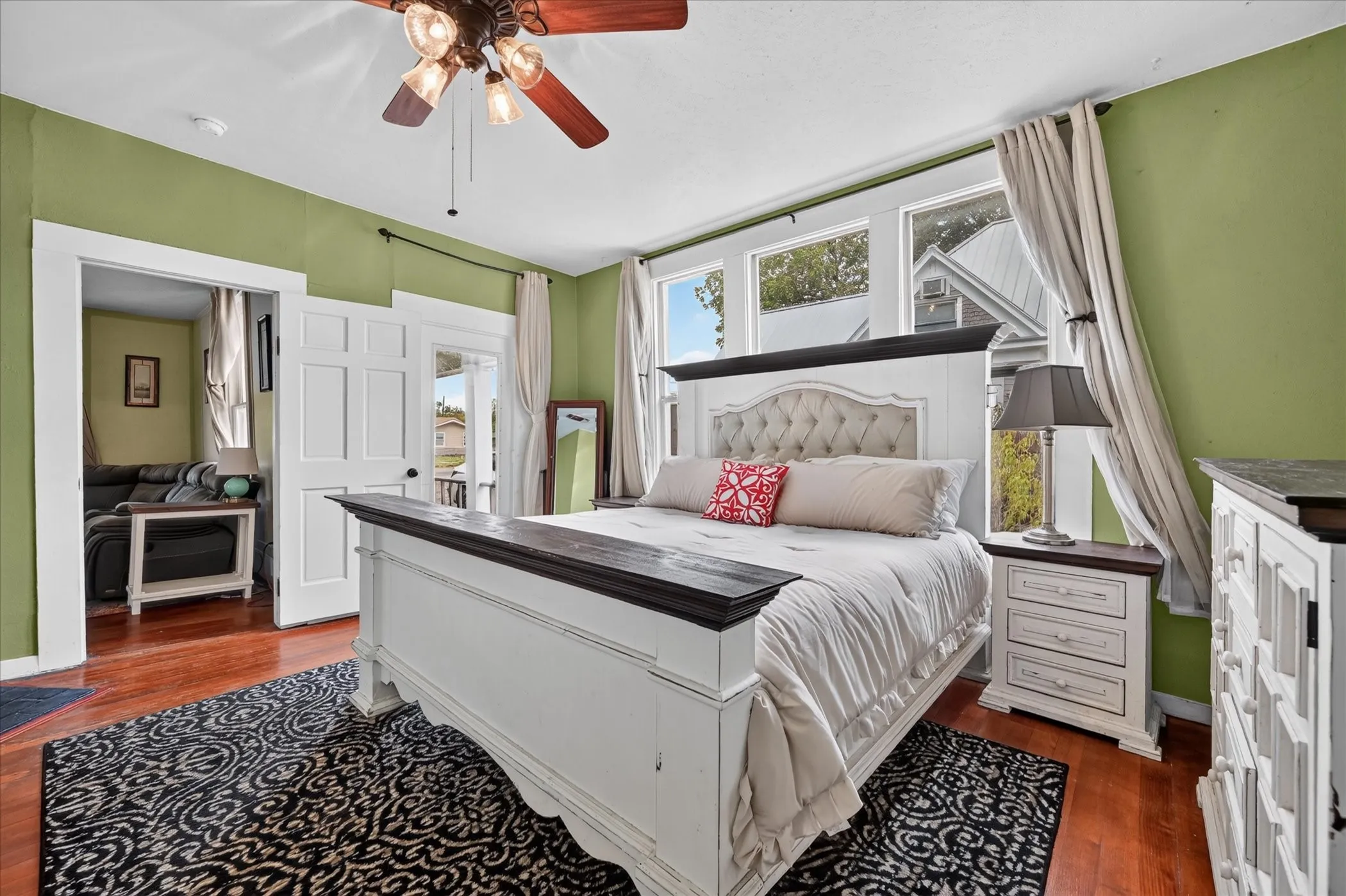 Hardwood-style flooring, ceiling fan with light fixture, multiple transom windows, and white trim throughout