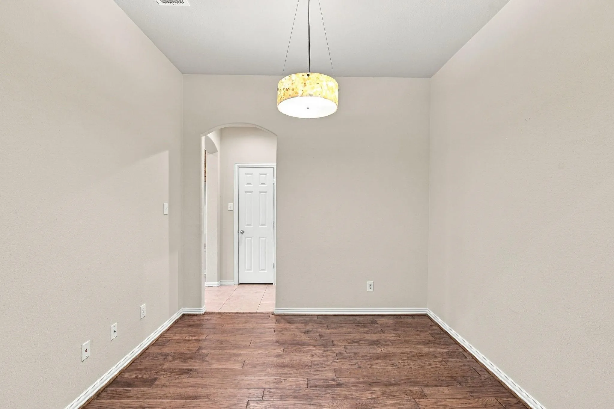 Wood-finish flooring, neutral wall tones, arched doorway, and a contemporary ceiling fixture
