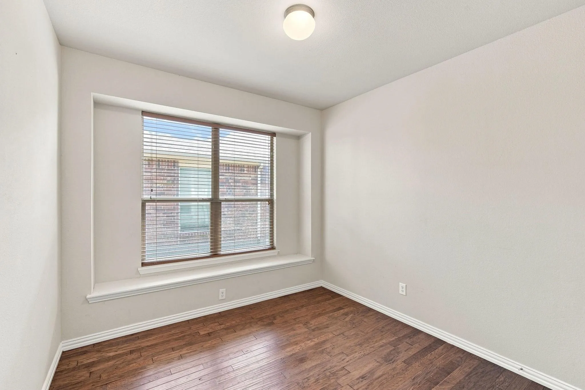 Hardwood flooring, window with blinds, recessed window ledge, and flush mount lighting