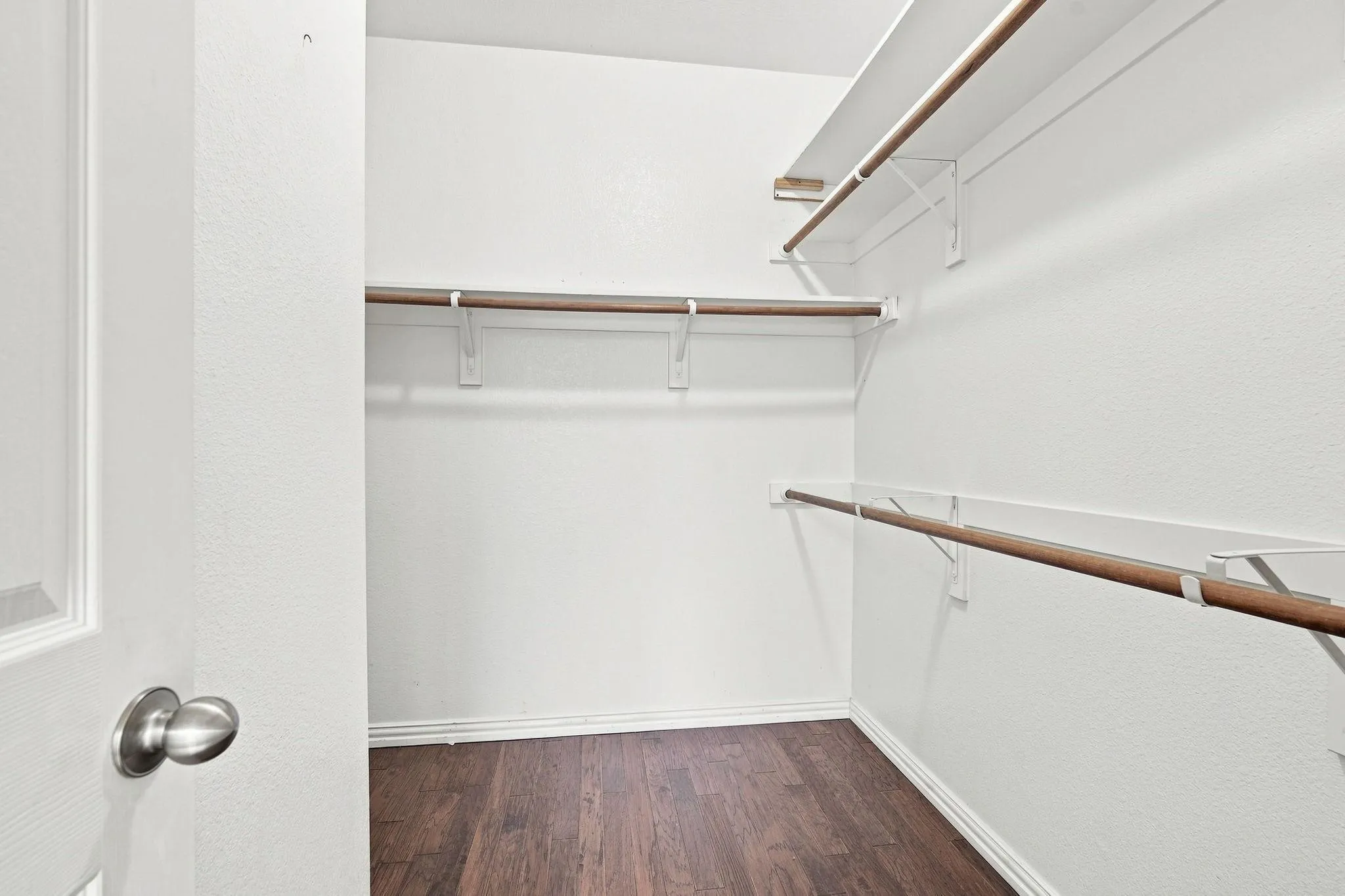 Walk-in closet with multi-level shelving and wood-finish flooring
