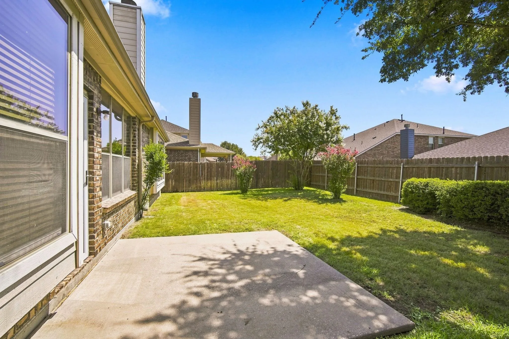 Expansive backyard featuring a concrete patio, manicured lawn, and privacy​​‌​​​​‌​​‌‌​‌‌​​​‌‌​‌​‌​‌​​​‌​​ fencing