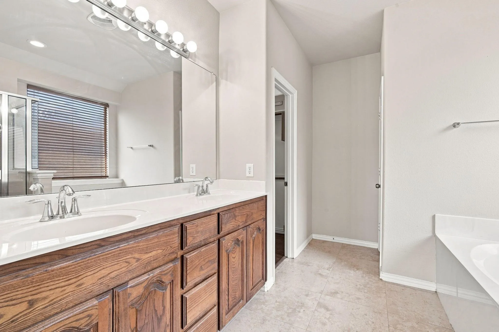Double vanity with wood-finish cabinetry, dual undermount sinks, and chrome faucets