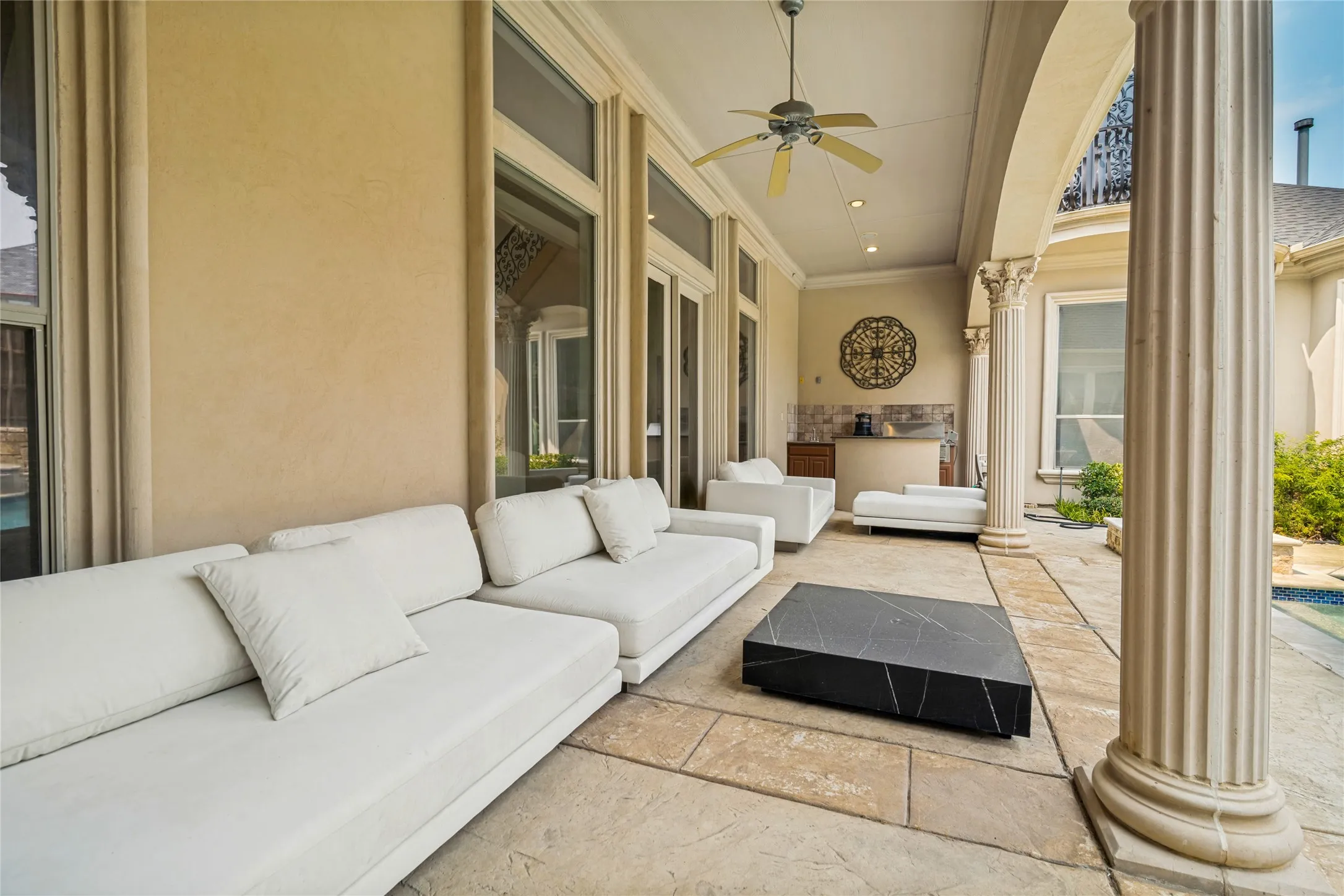 Expansive covered patio featuring a built-in outdoor kitchen, recessed lighting, and a ceiling fan