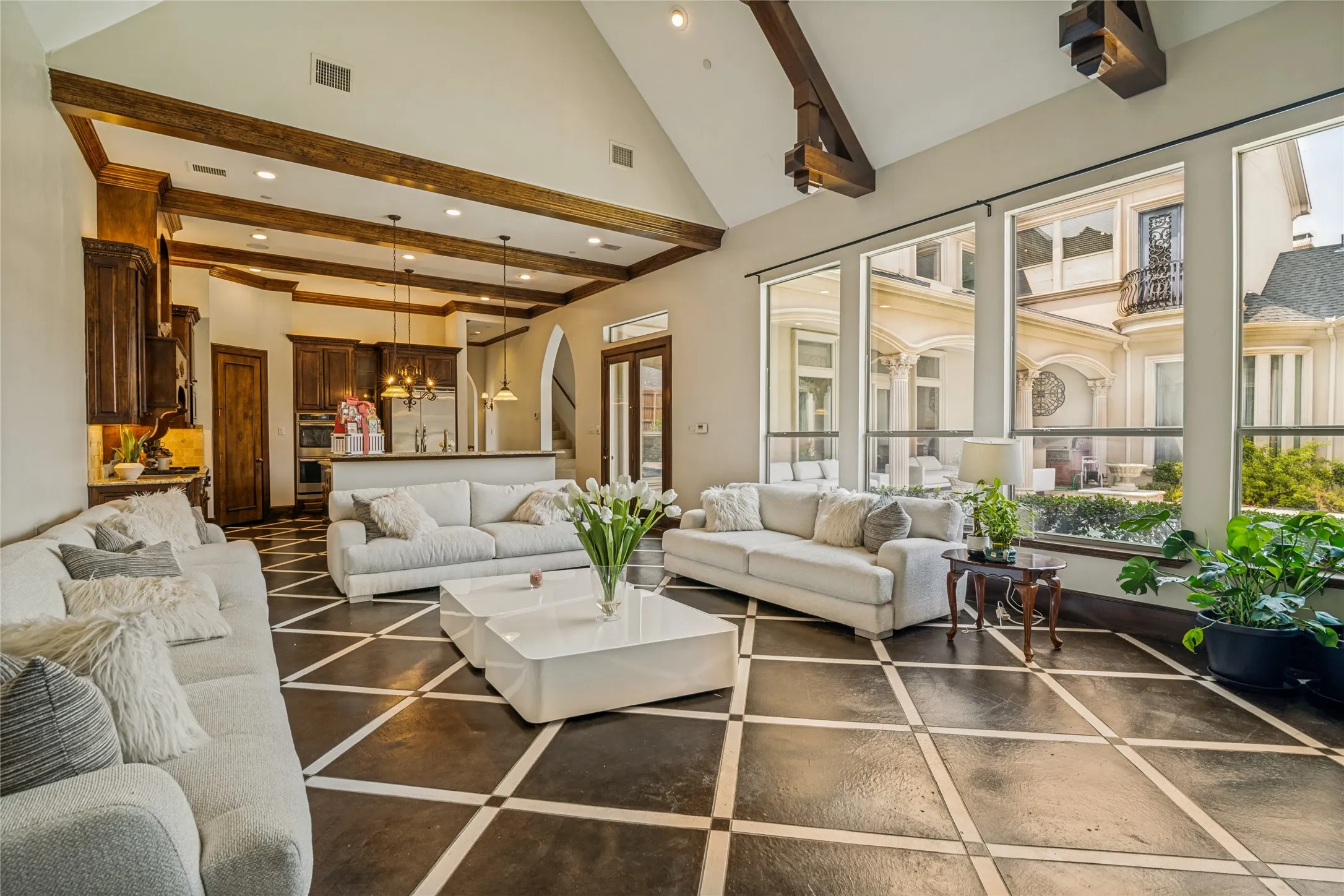 Vaulted ceiling with exposed wood beams, large format tiled flooring, floor-to-ceiling windows, built-in cabinetry, and integrated kitchen appliances