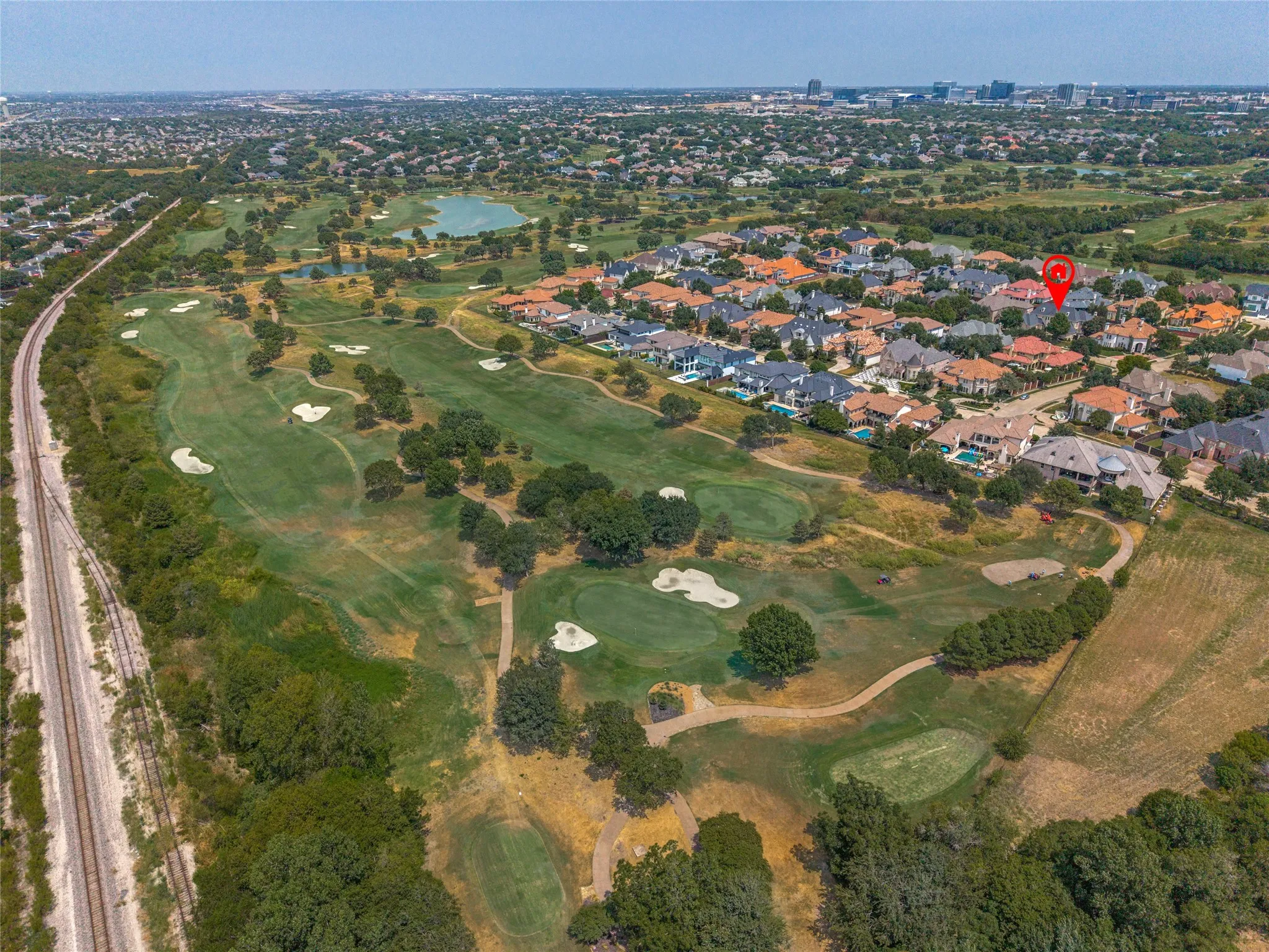 Expansive golf course property with mature trees, sand traps, and a water feature