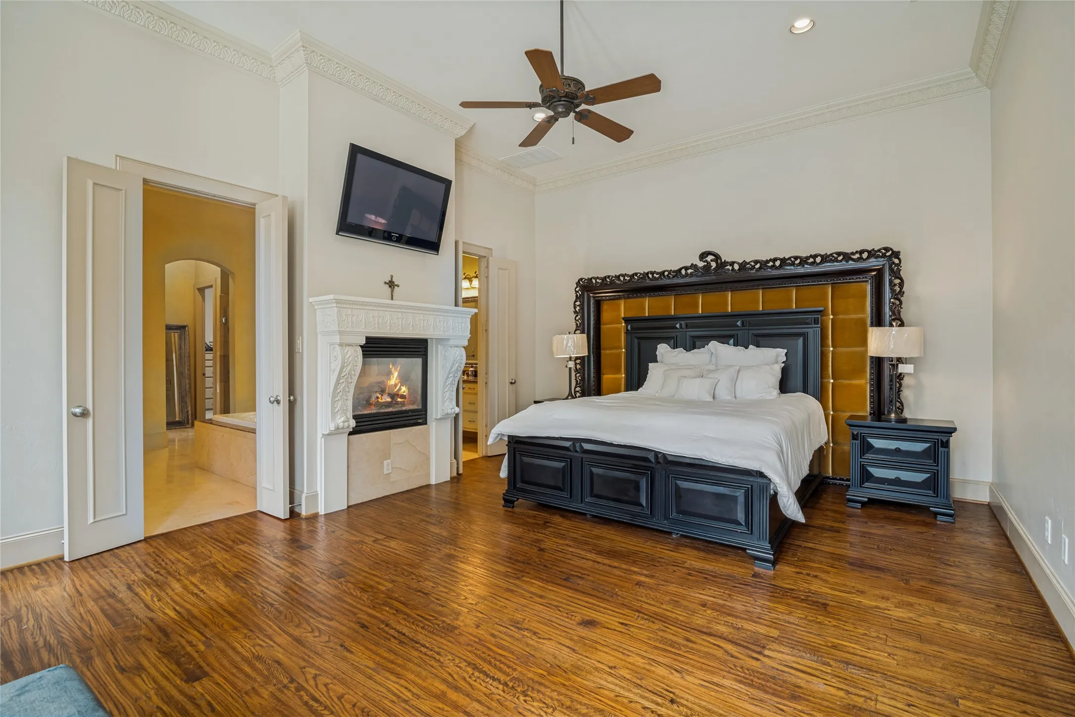Wood-finish flooring, crown molding, built-in fireplace with a mantel, recessed lighting, and a ceiling fan