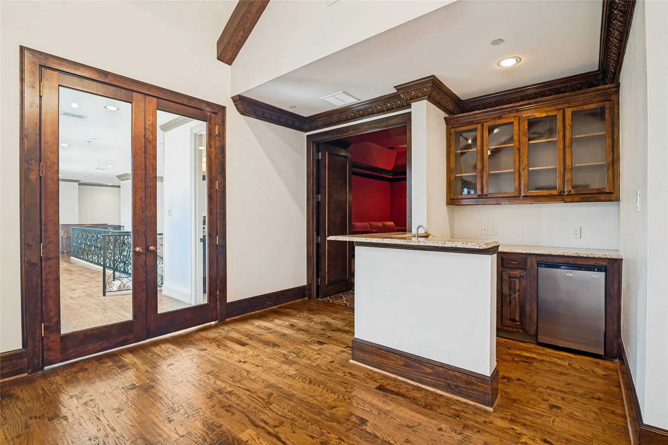 Built-in wet bar with a stainless steel appliance, granite-style countertop, and glass-front upper cabinetry