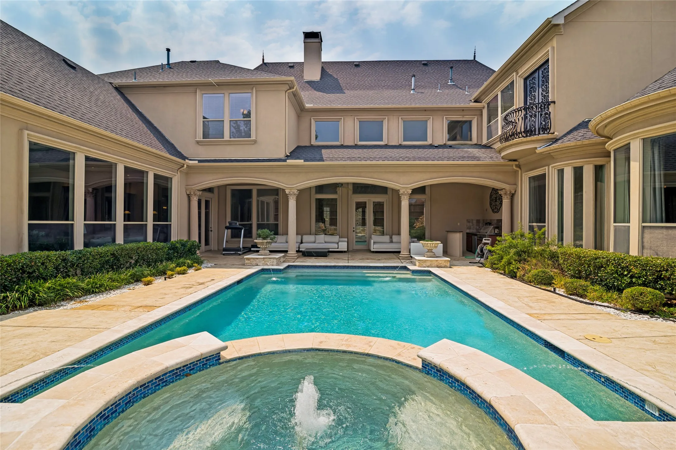 Expansive outdoor living area featuring a rectangular swimming pool, integrated spa, and surrounding hardscaping