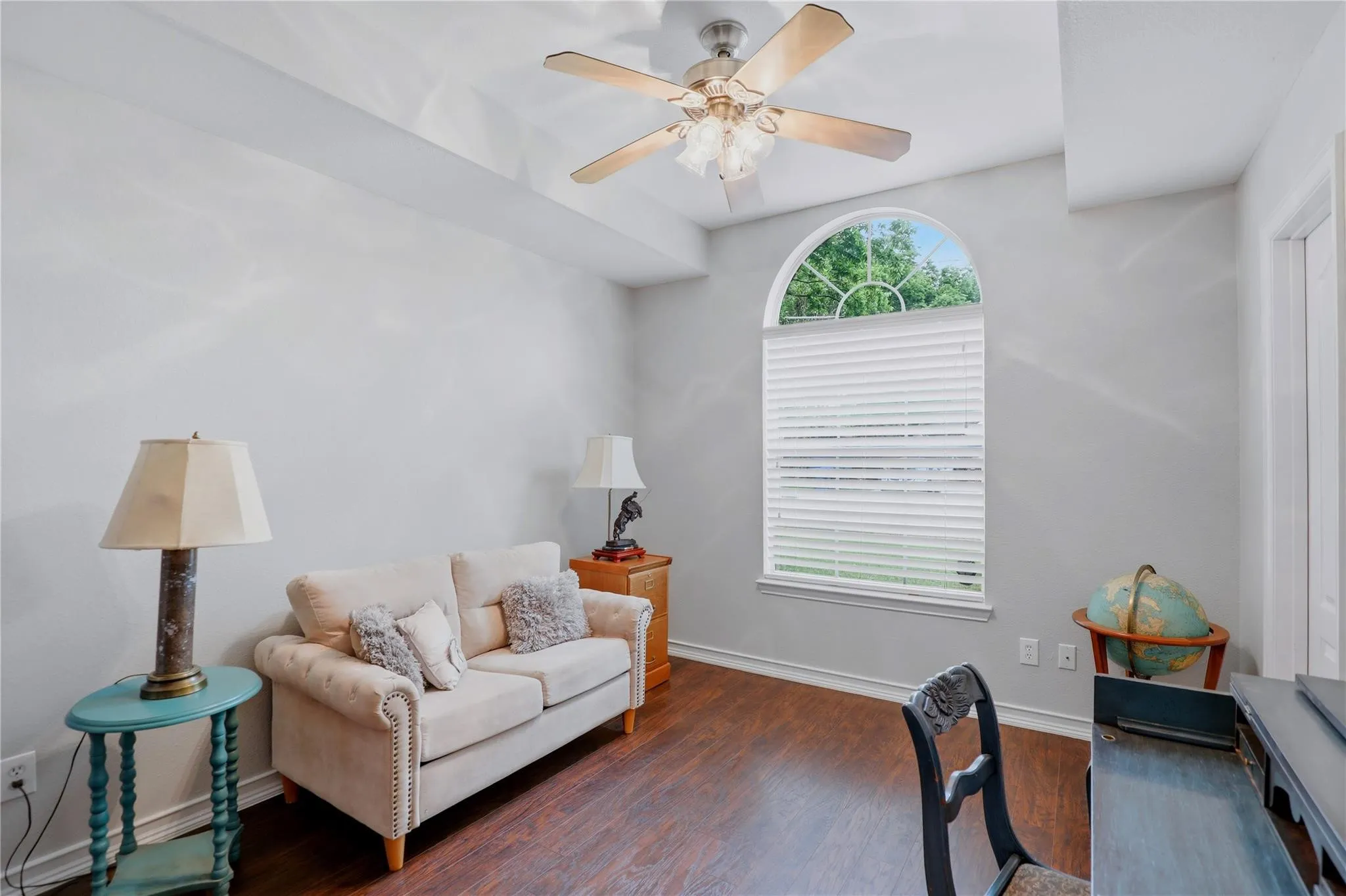 Arched window with blinds, ceiling fan with integrated lighting, wood-finish flooring, and recessed ceiling detail