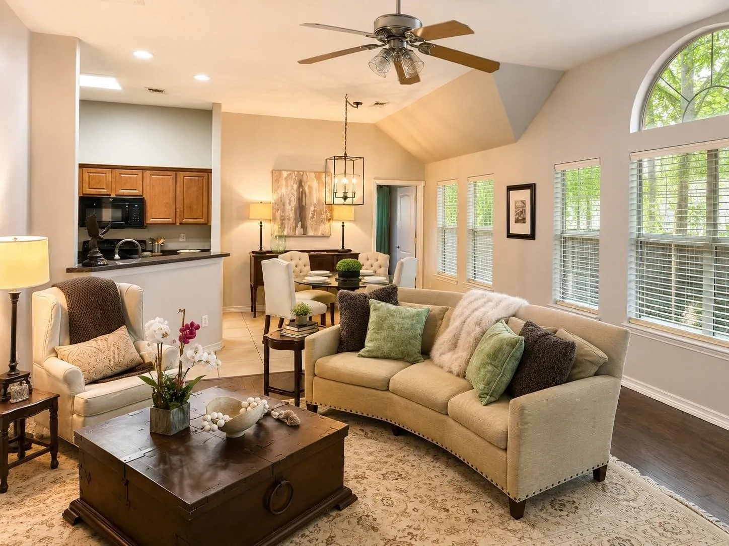 Vaulted ceiling with a ceiling fan, arched transom window, recessed lighting, wood-finish flooring, and a kitchen pass-through