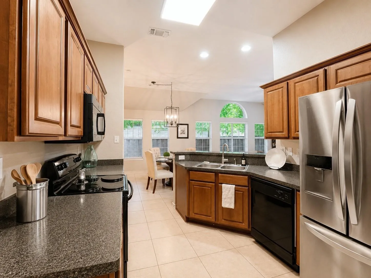 Kitchen featuring wood cabinetry, dark speckled countertops, and stainless steel appliances