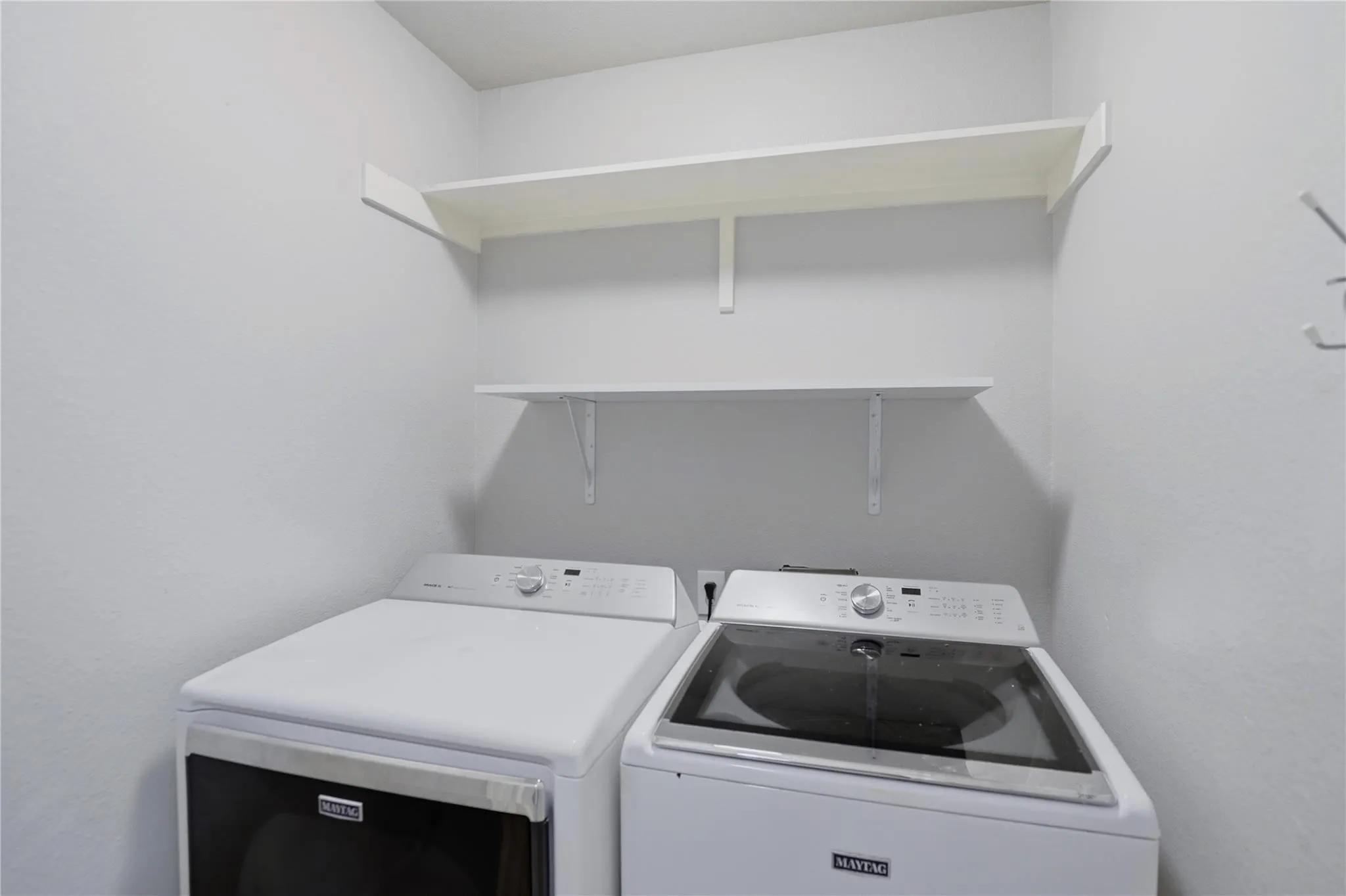Laundry area with white walls and dual built-in shelving