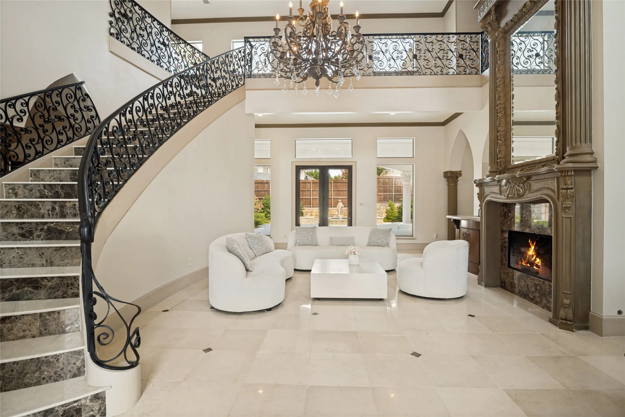 Soaring two-story entry hall anchored by a dramatic curved staircase with ornamental wrought-iron railings and marble-finish treads