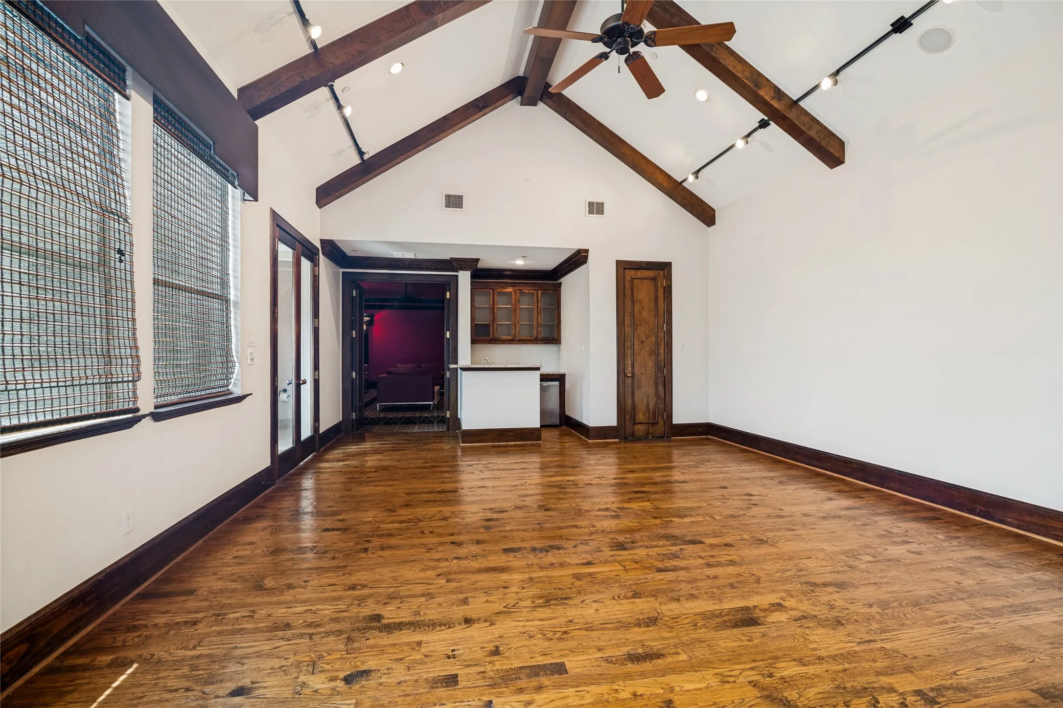 Vaulted ceiling with exposed wood beams, wood-finish flooring, built-in cabinetry, and a ceiling fan with integrated lighting