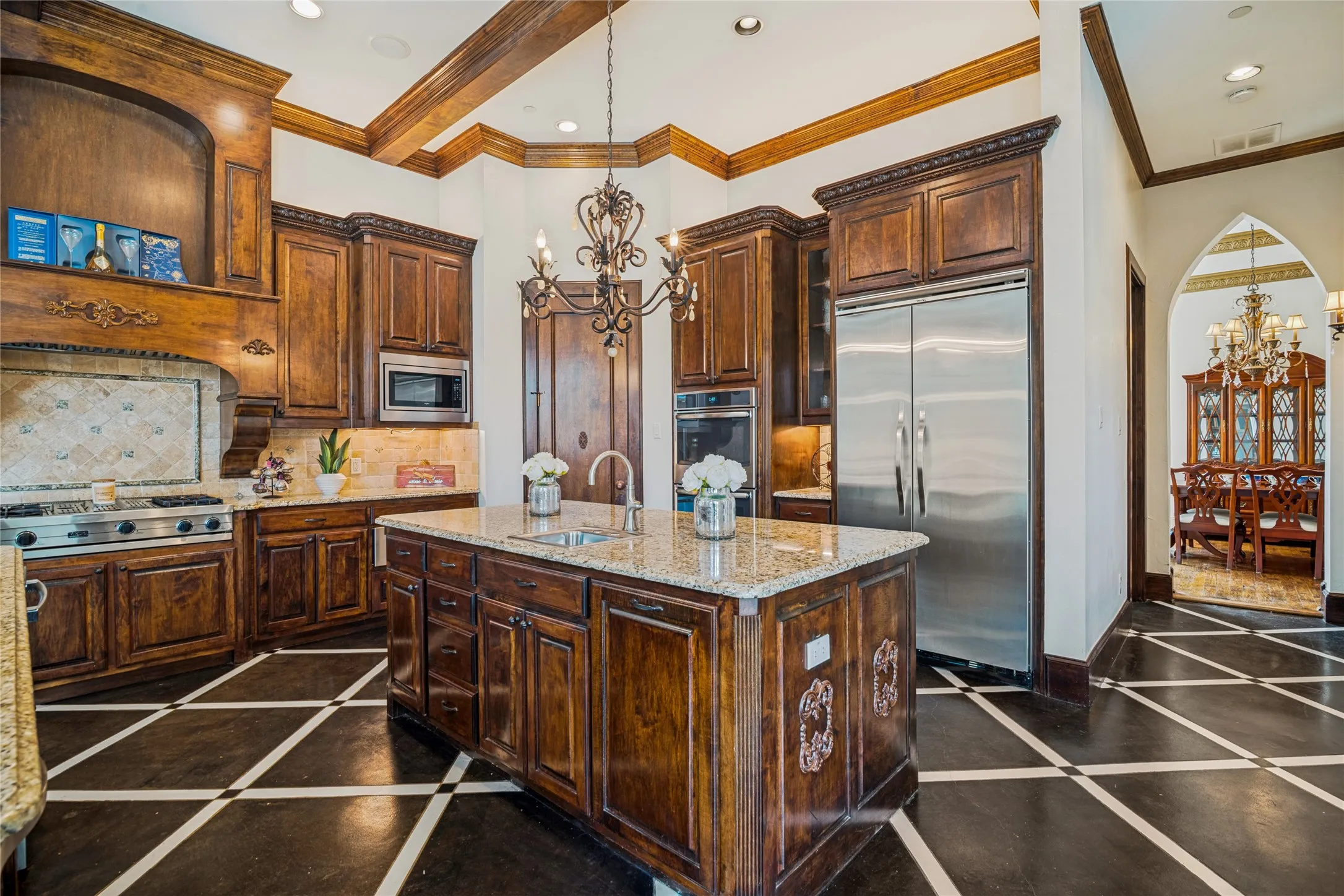 Gourmet kitchen featuring rich wood cabinetry, granite countertops, stainless steel appliances, a center island with sink, and a decorative tile backsplash
