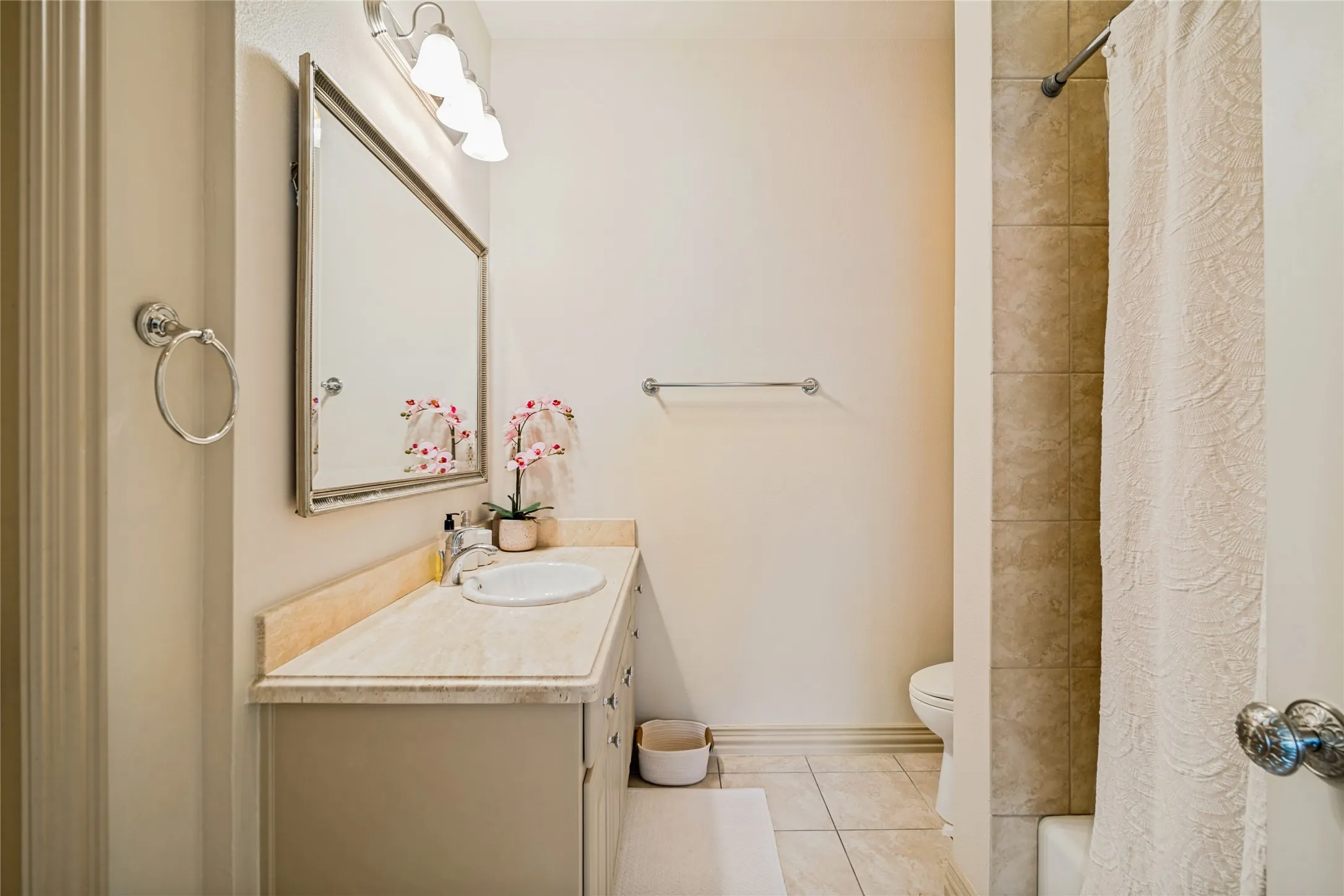 Bathroom featuring a wood-finish vanity with an integrated sink, ceramic tile flooring, and brushed nickel hardware and fixtures