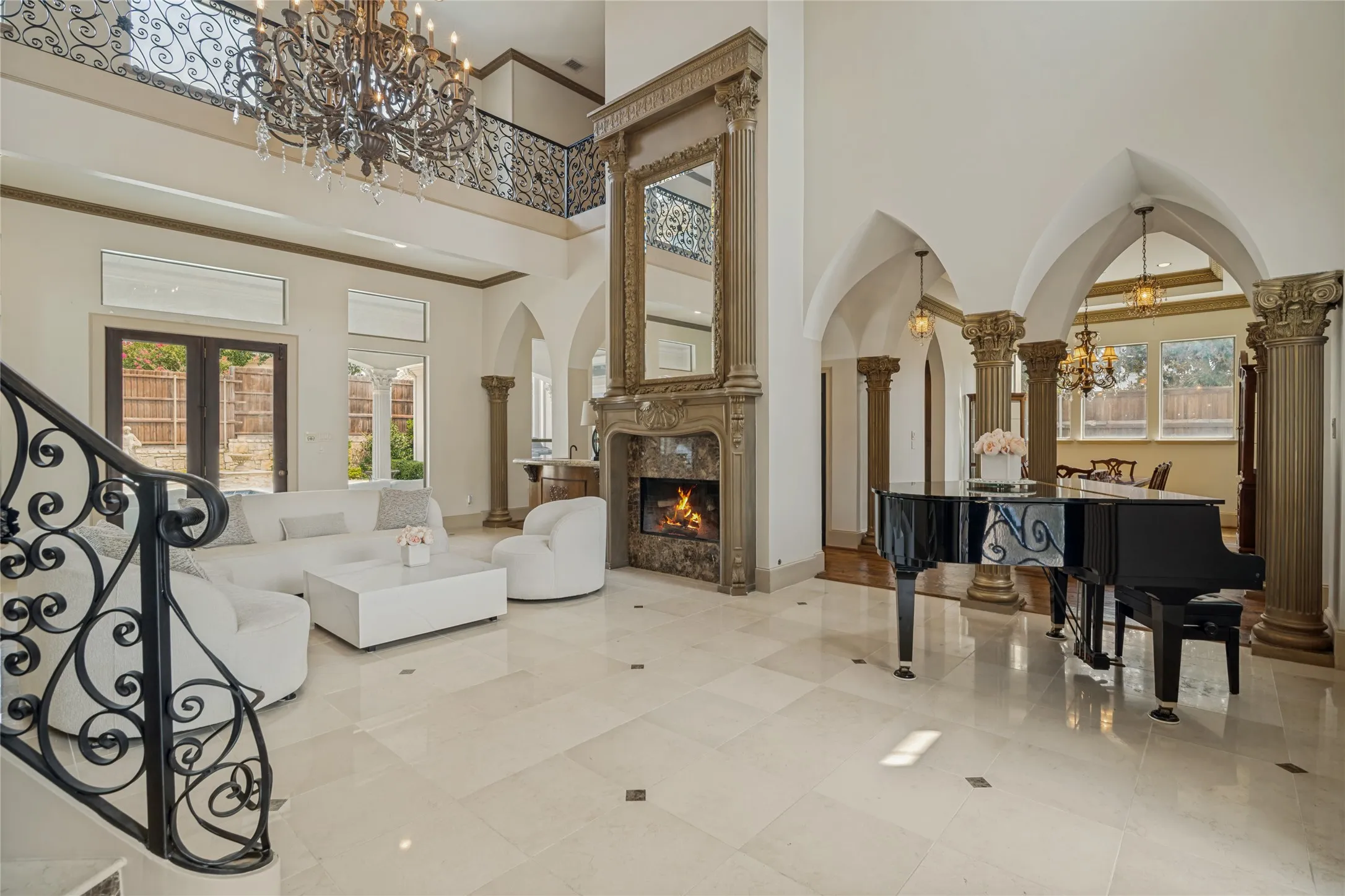Expansive living area with high ceilings, polished tile flooring, decorative fireplace with ornate mantel, and detailed archways
