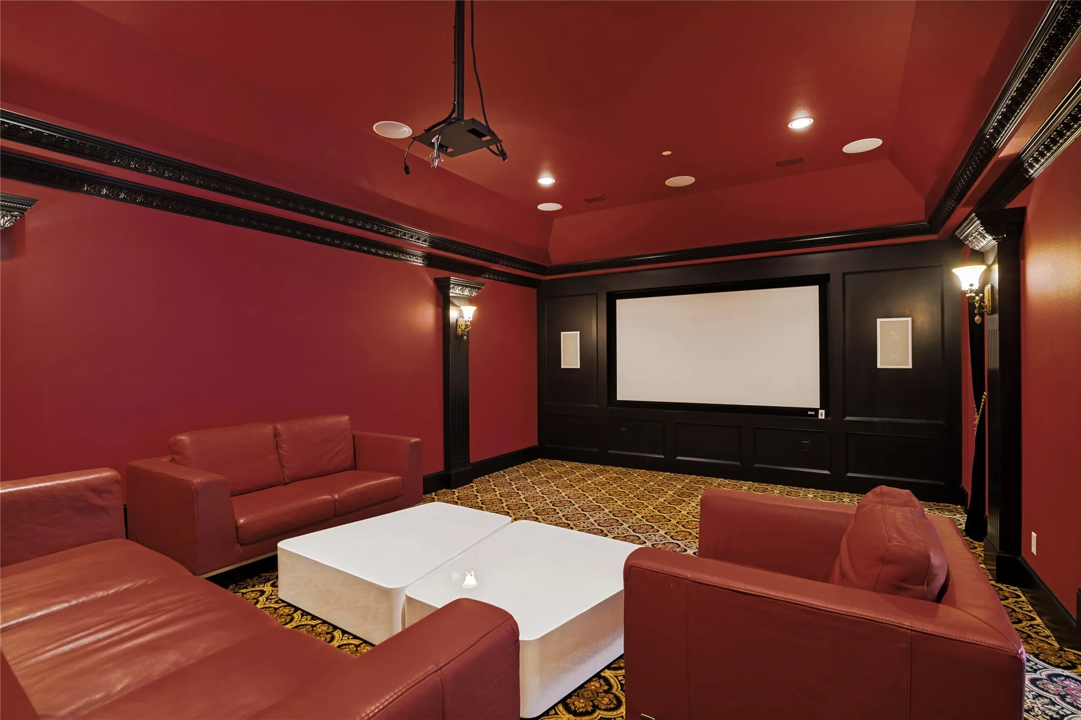 Built-in projector with a large screen, recessed ceiling lighting, wall-mounted sconces, and crown molding accents