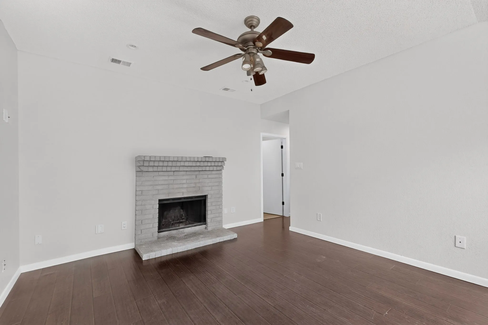 Brick fireplace with hearth, wood-finish flooring, ceiling fan, and recessed lighting