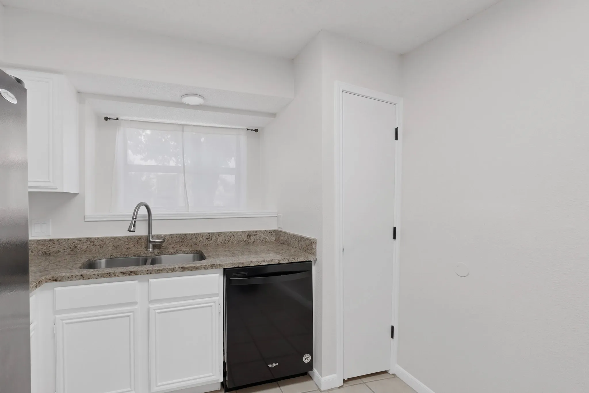 White cabinetry, stainless steel sink, pull-down faucet, integrated dishwasher, and light-toned countertops