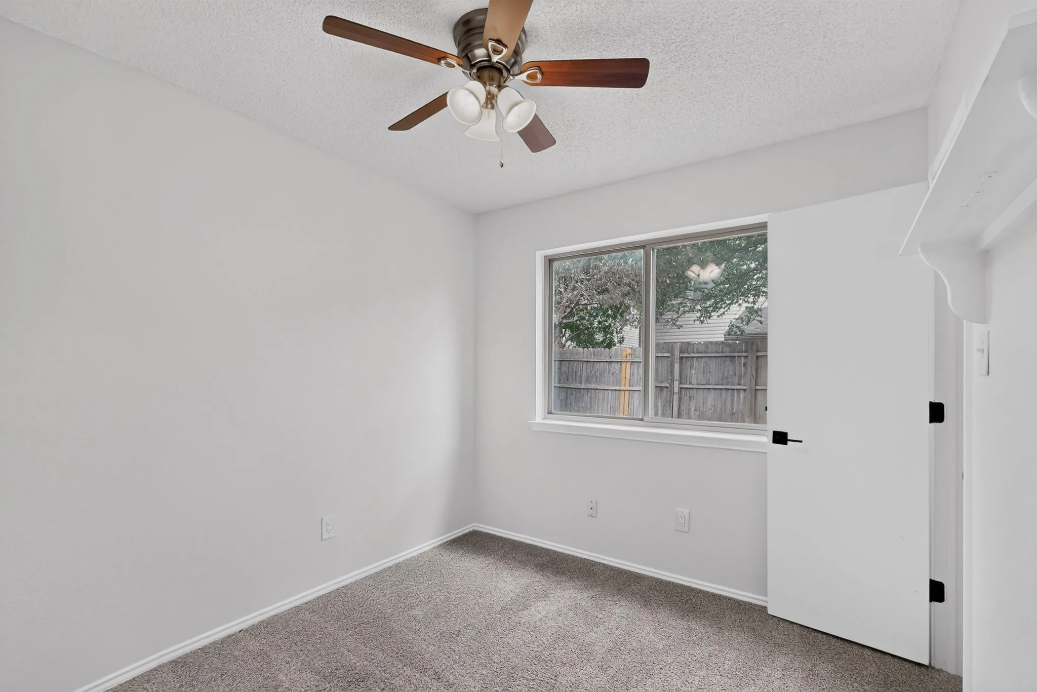 Recessed window with exterior yard visibility, ceiling fan with integrated lighting, textured ceiling, and gray carpet