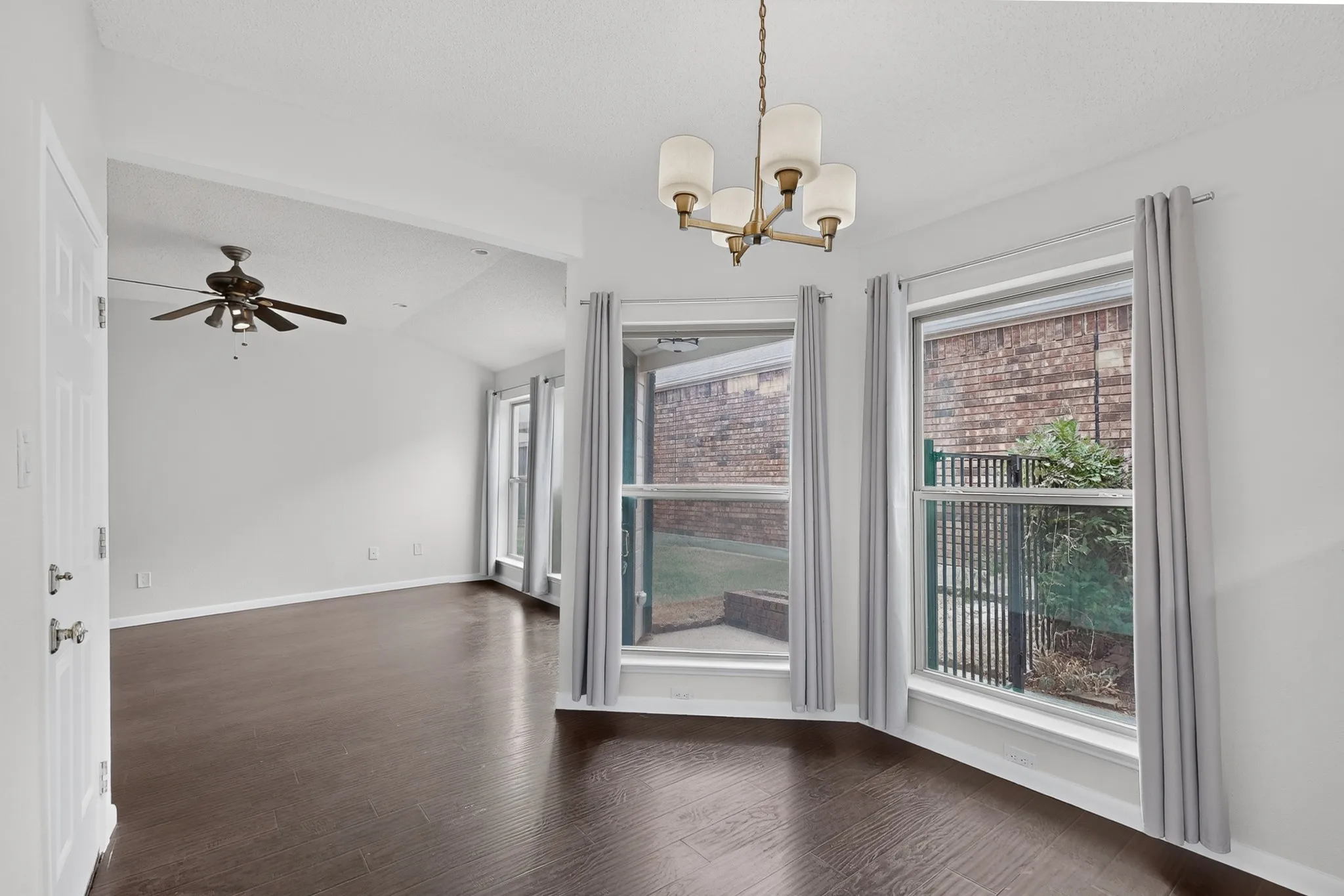Vaulted ceiling, dark wood-finish flooring, contemporary chandelier, ceiling fan, and multiple windows