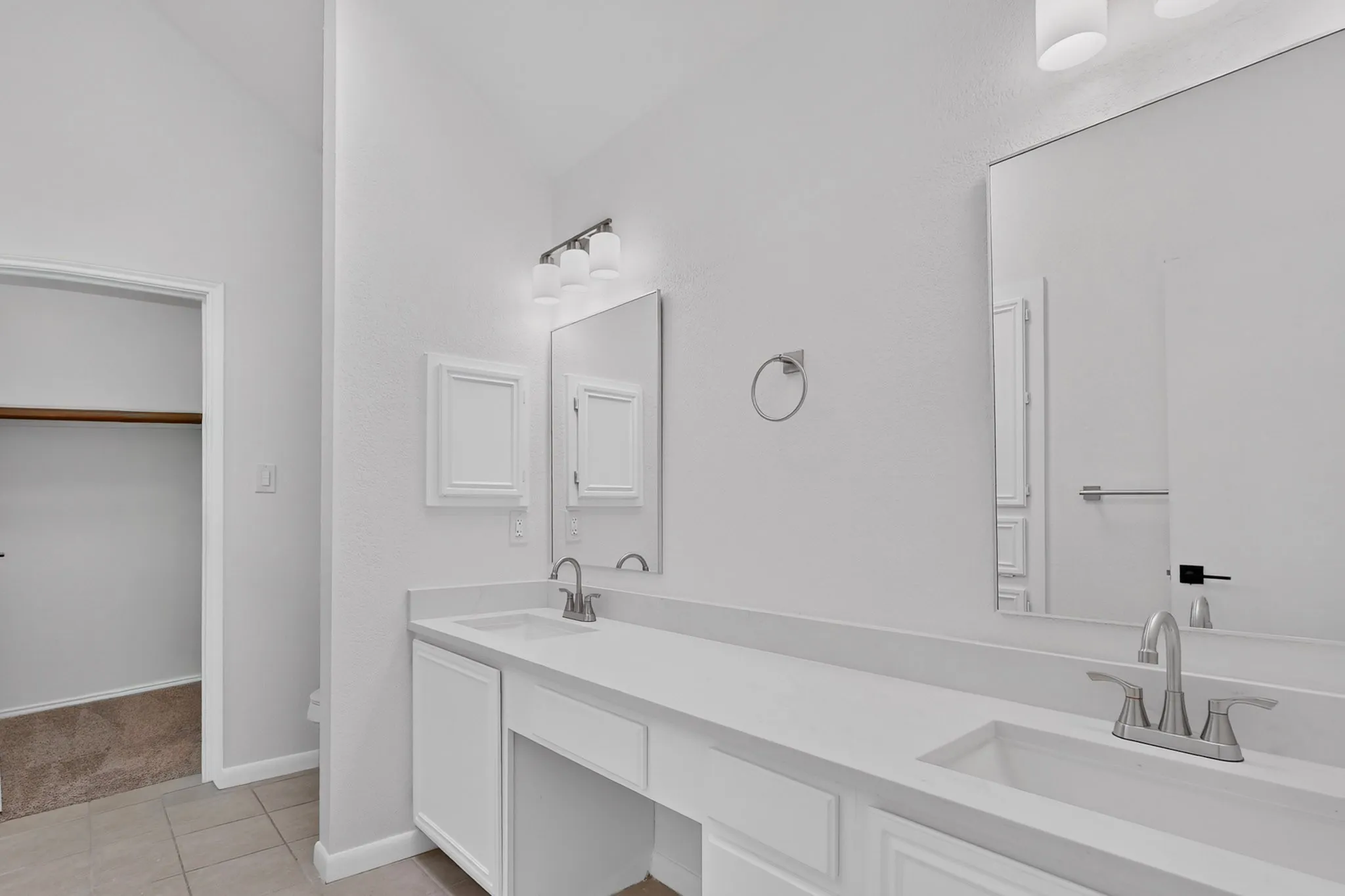 Dual vanity with integrated sinks, brushed nickel fixtures, wall-mounted mirrors, and built-in cabinetry