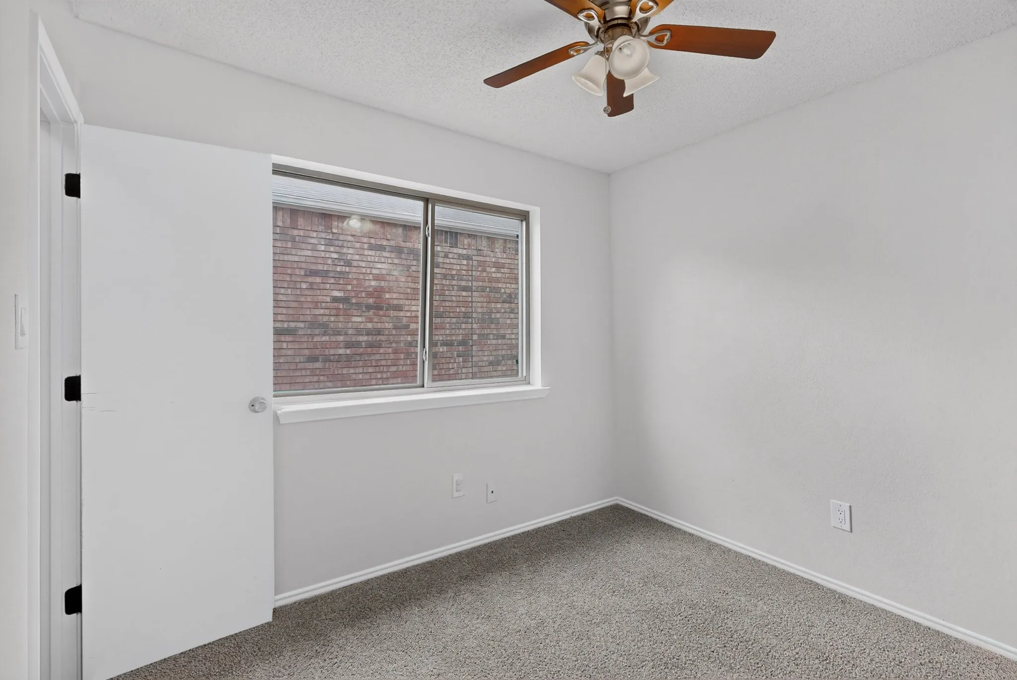Light gray walls with gray carpet flooring and a ceiling fan