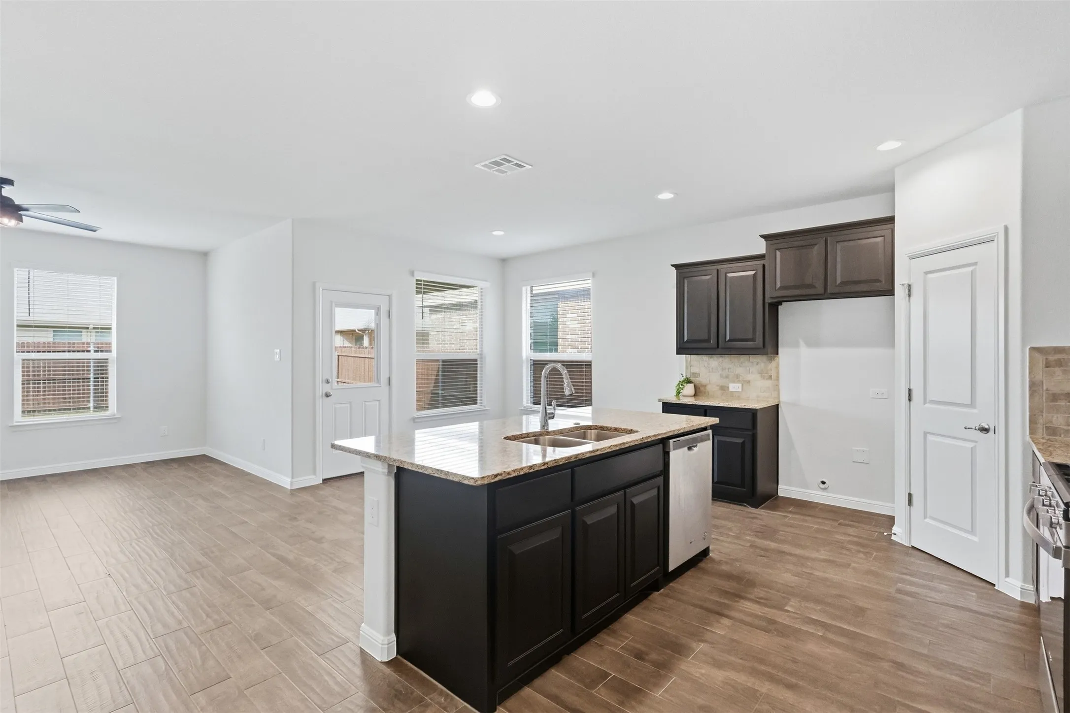 Kitchen island with granite countertop, double basin sink, and stainless steel dishwasher