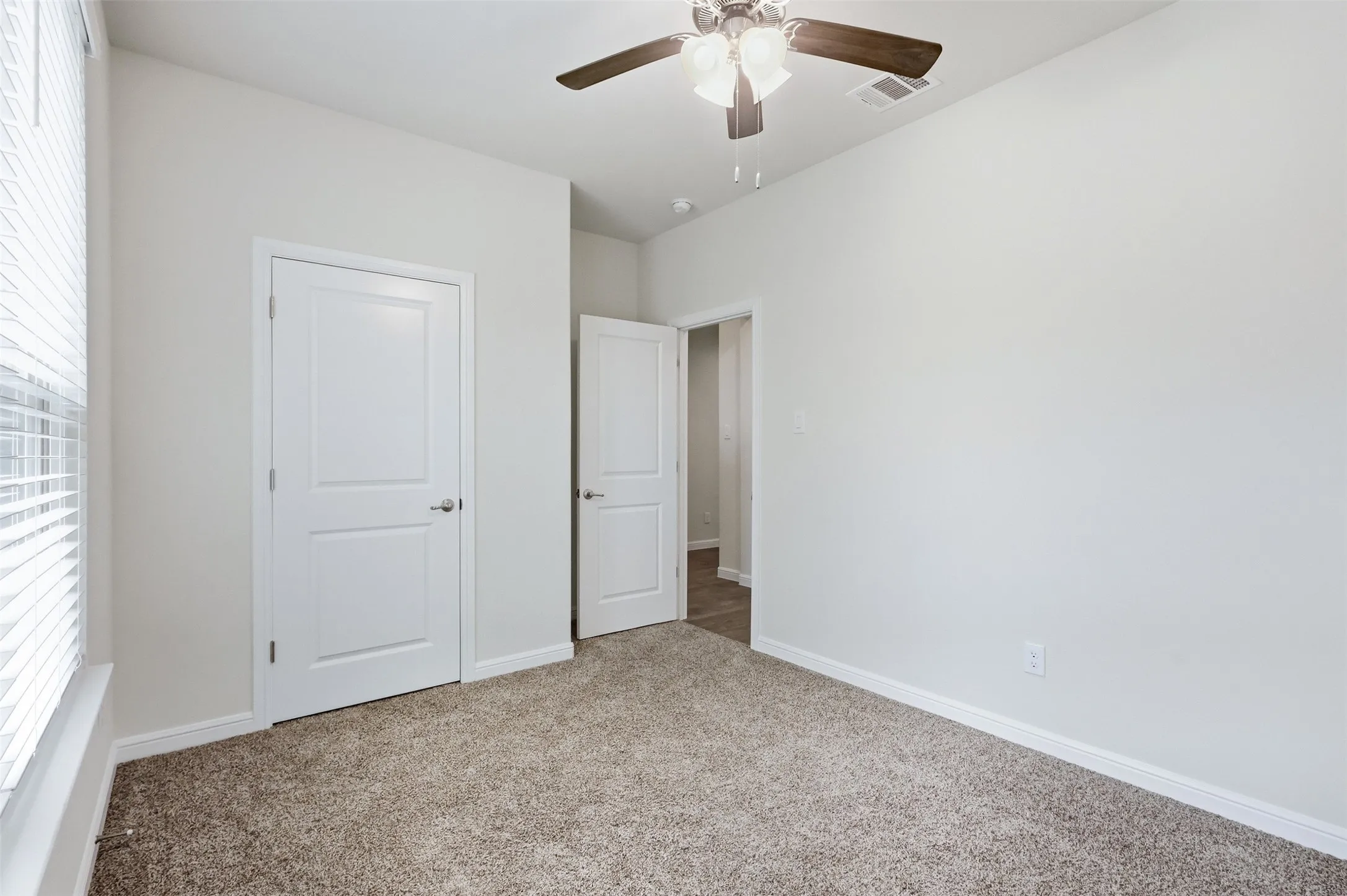 Neutral tone wall paint, textured carpeting, contemporary ceiling fan, bright white trim, and paneled interior doors