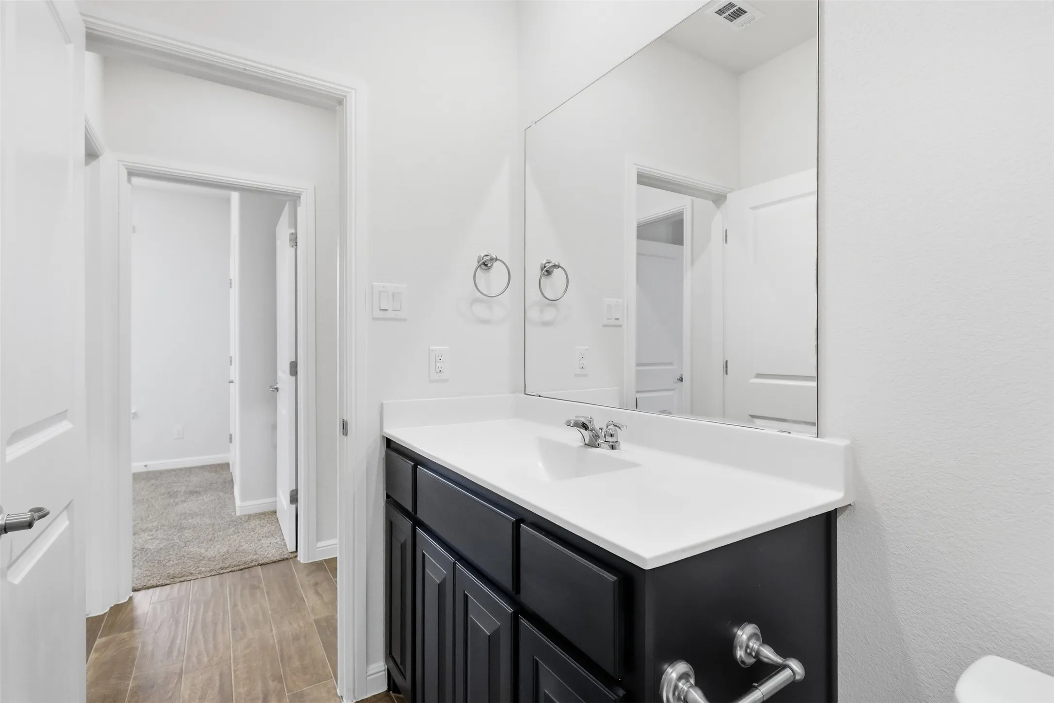 Modern vanity featuring a single basin sink, chrome faucet, and dark wood-finish cabinetry