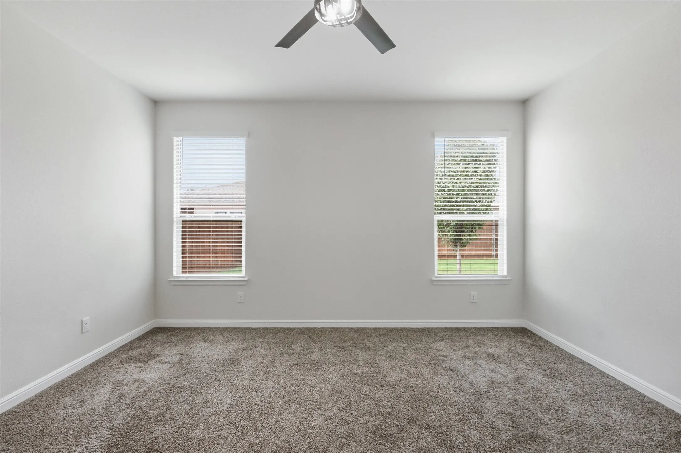 Recessed lighting, ceiling fan with brushed metal accents, two windows with blinds, and neutral carpeting