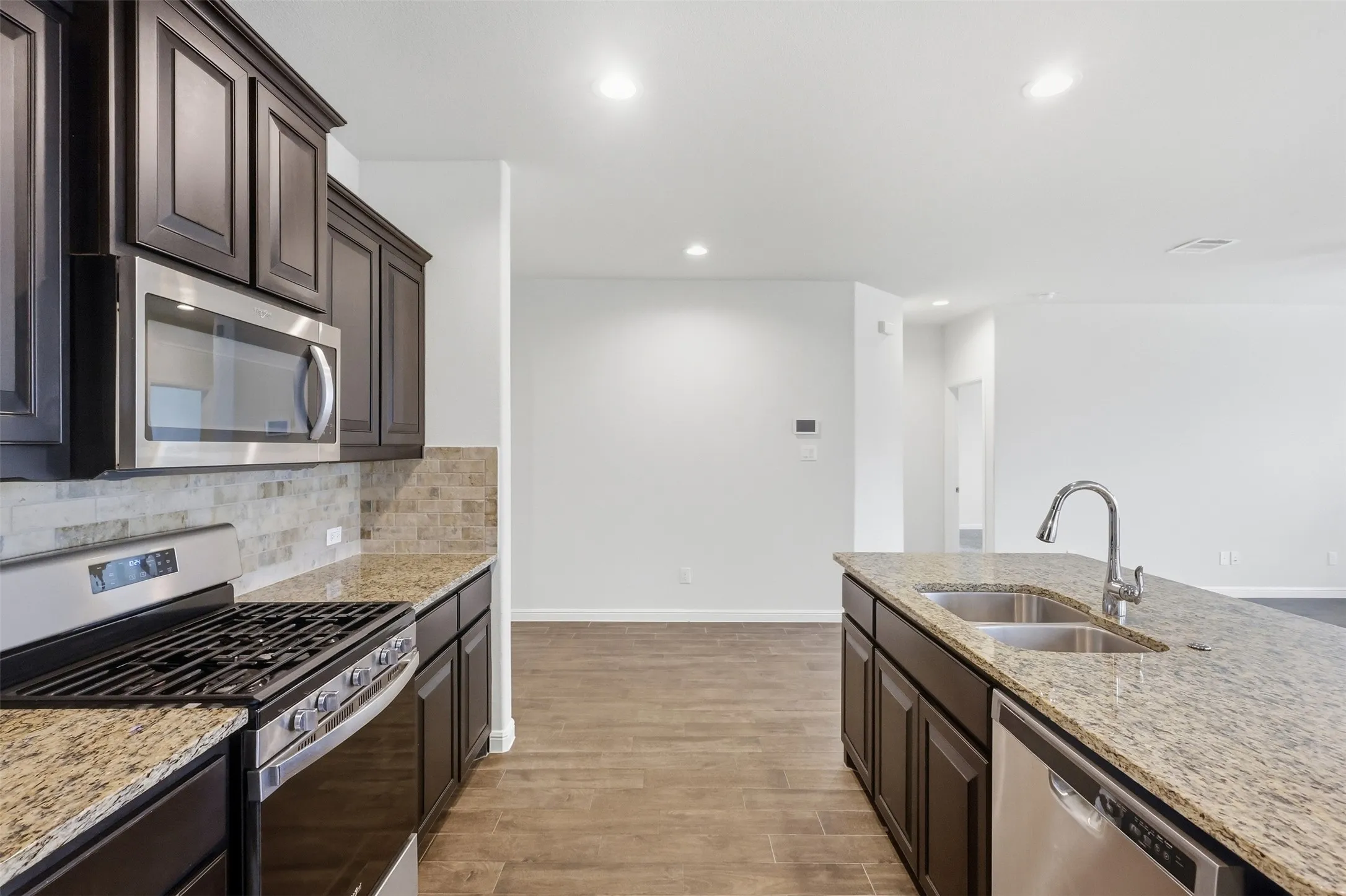 Kitchen featuring a stainless steel gas range, over-range microwave, double basin sink, and Tile flooring