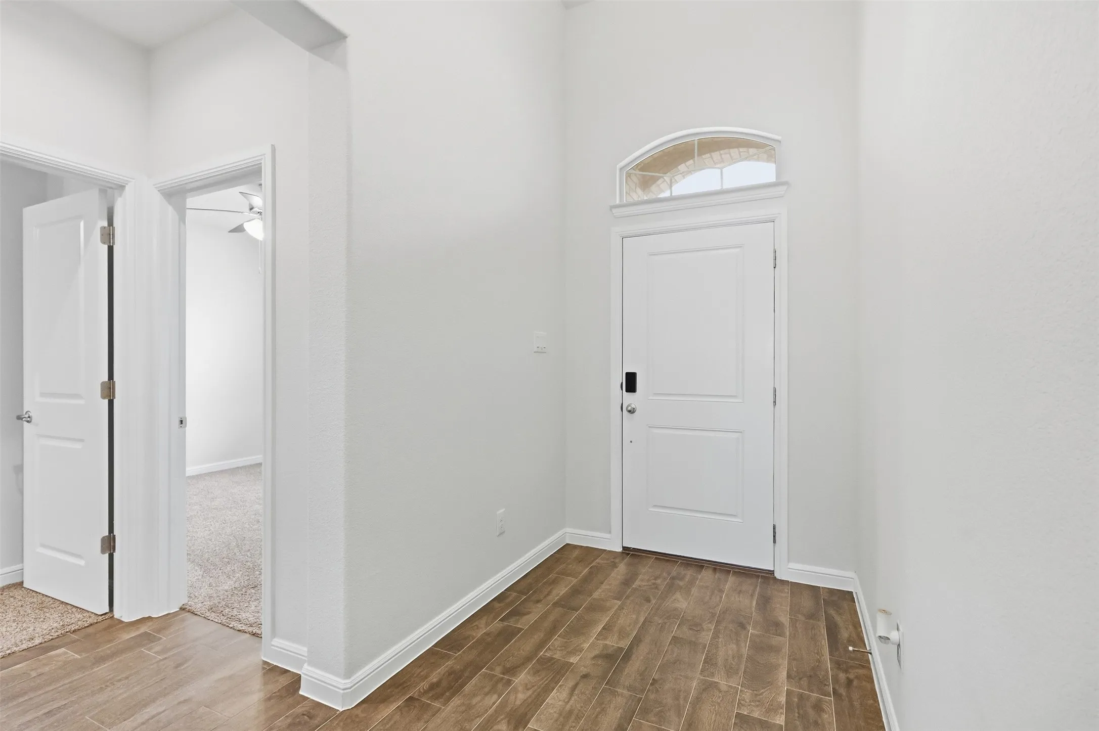 Entryway featuring Tile flooring, a white paneled door with smart lock, and an arched transom window