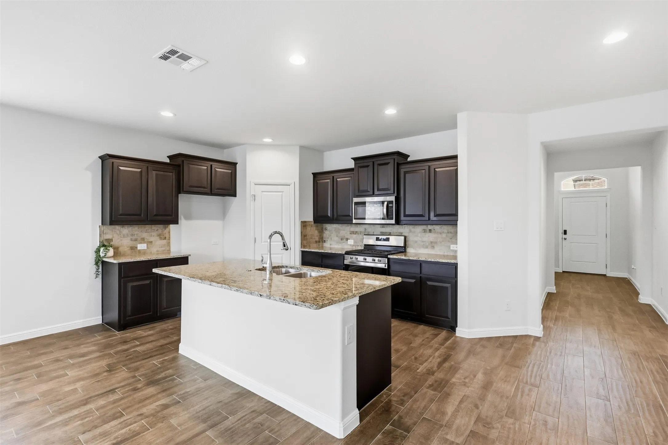 Kitchen featuring dark wood-finish cabinetry, granite countertops, and a tiled backsplash