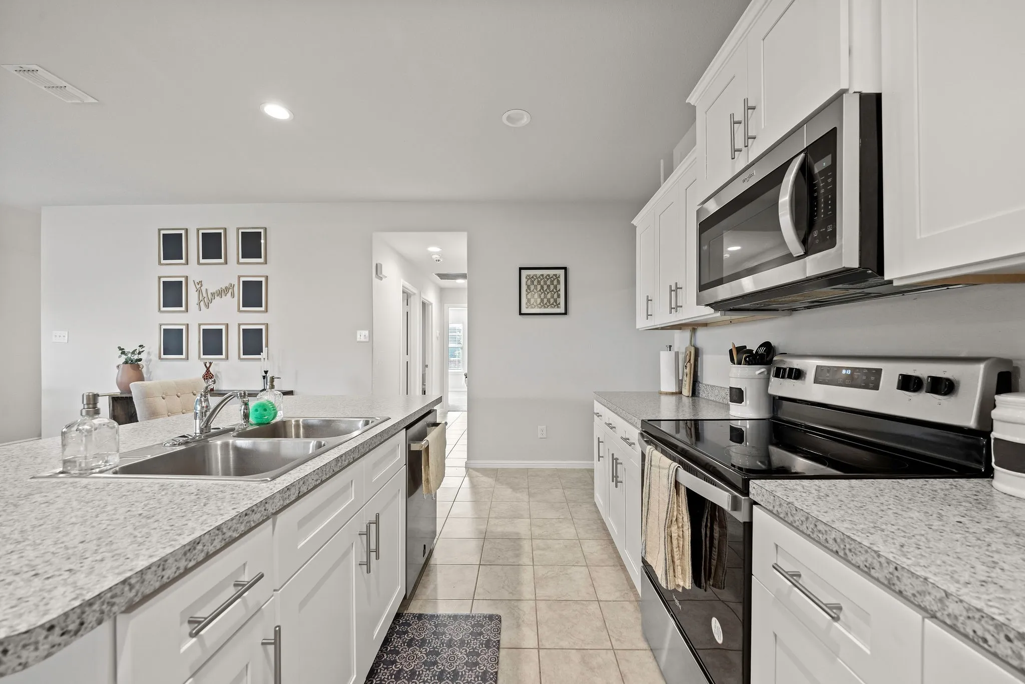 Kitchen featuring appliances with stainless steel finishes, light tile patterned flooring, light countertops, white cabinetry, and recessed lighting