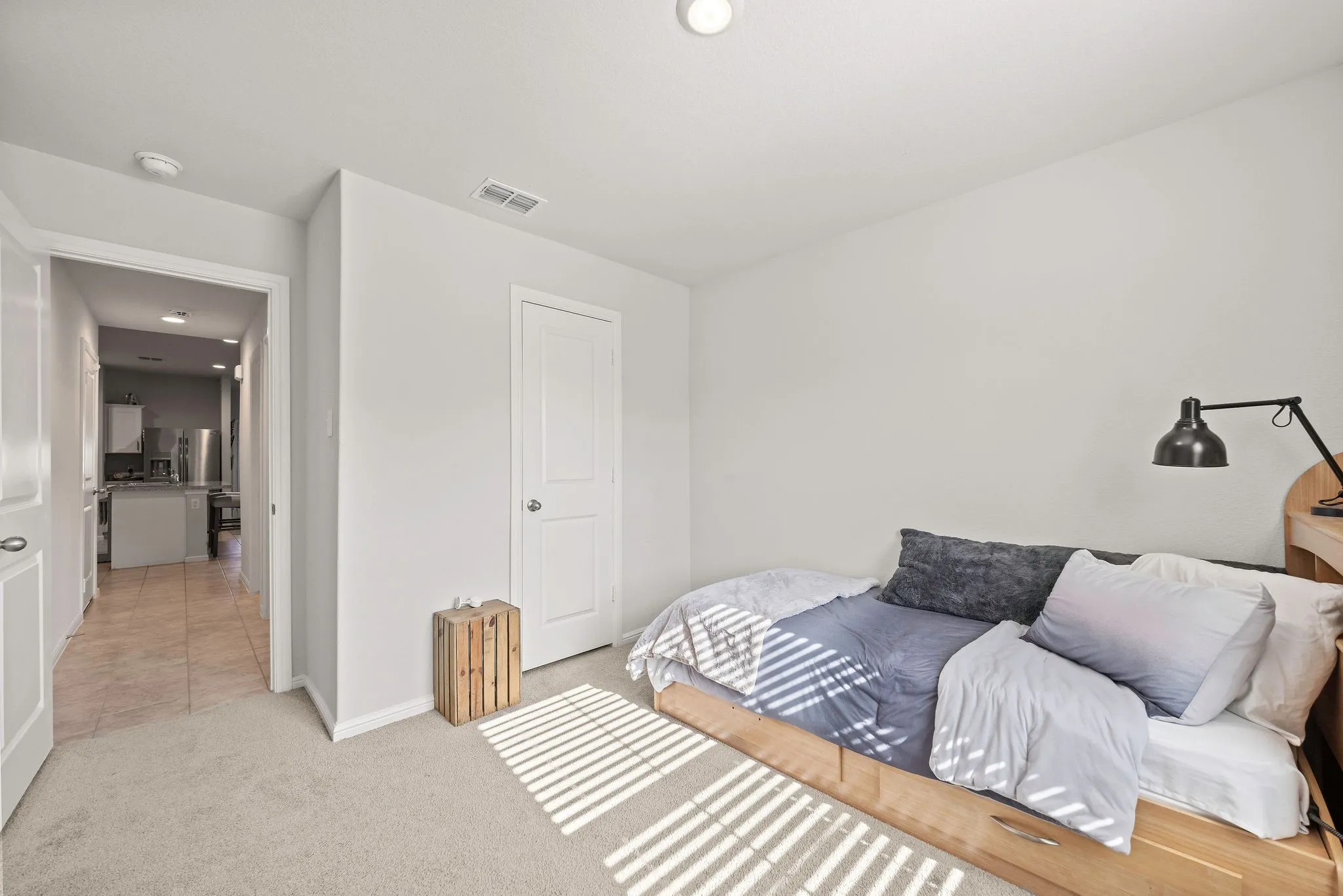 Bedroom featuring light colored carpet and stainless steel refrigerator with ice dispenser