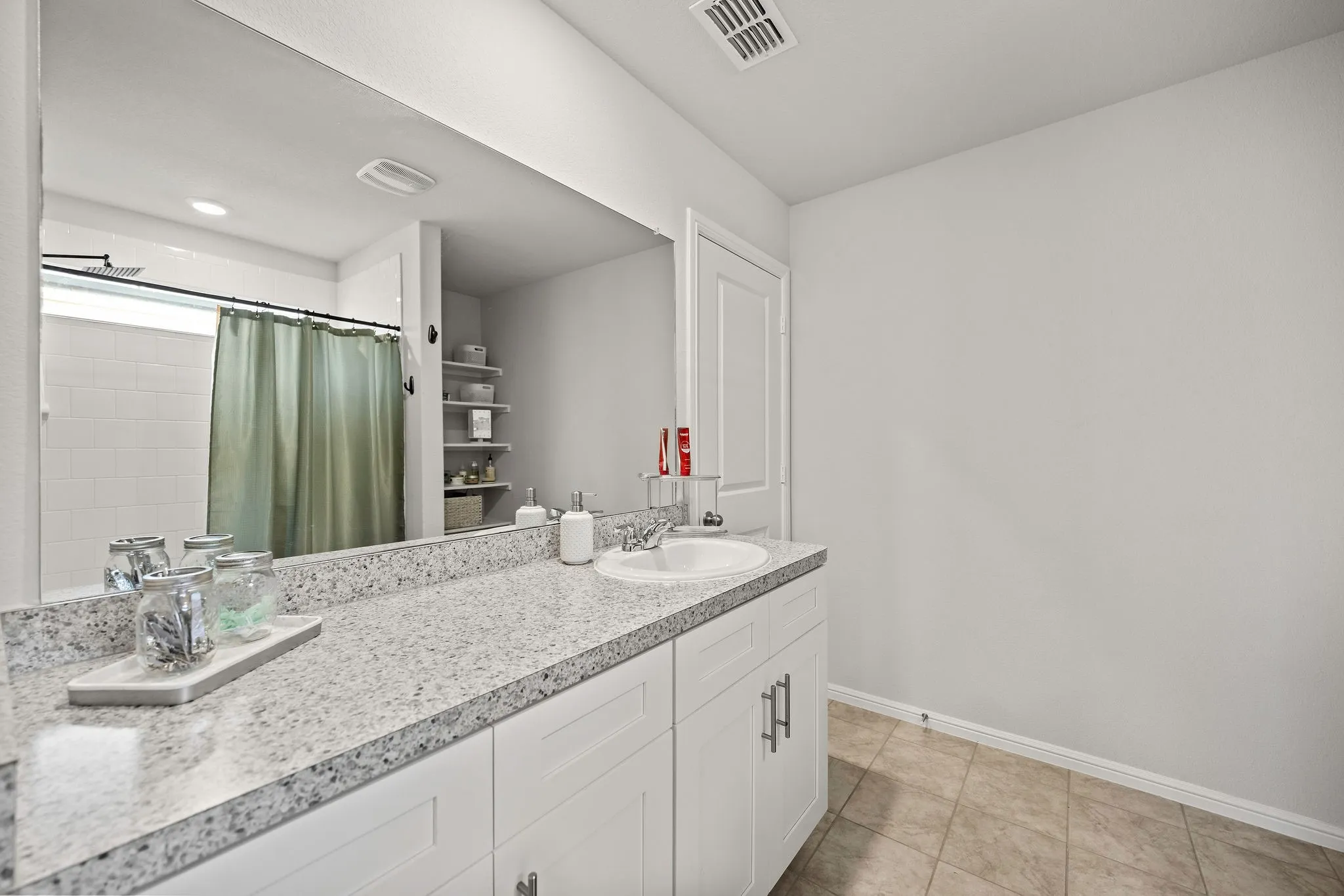 Bathroom with double vanity, a shower with curtain, and tile patterned flooring