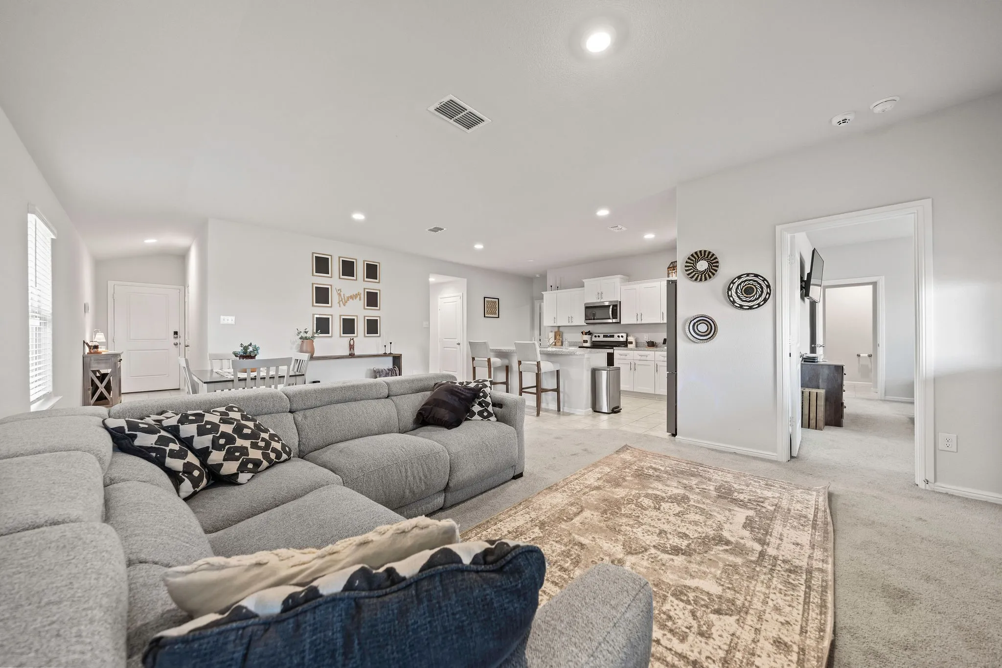 Living area with light colored carpet and recessed lighting