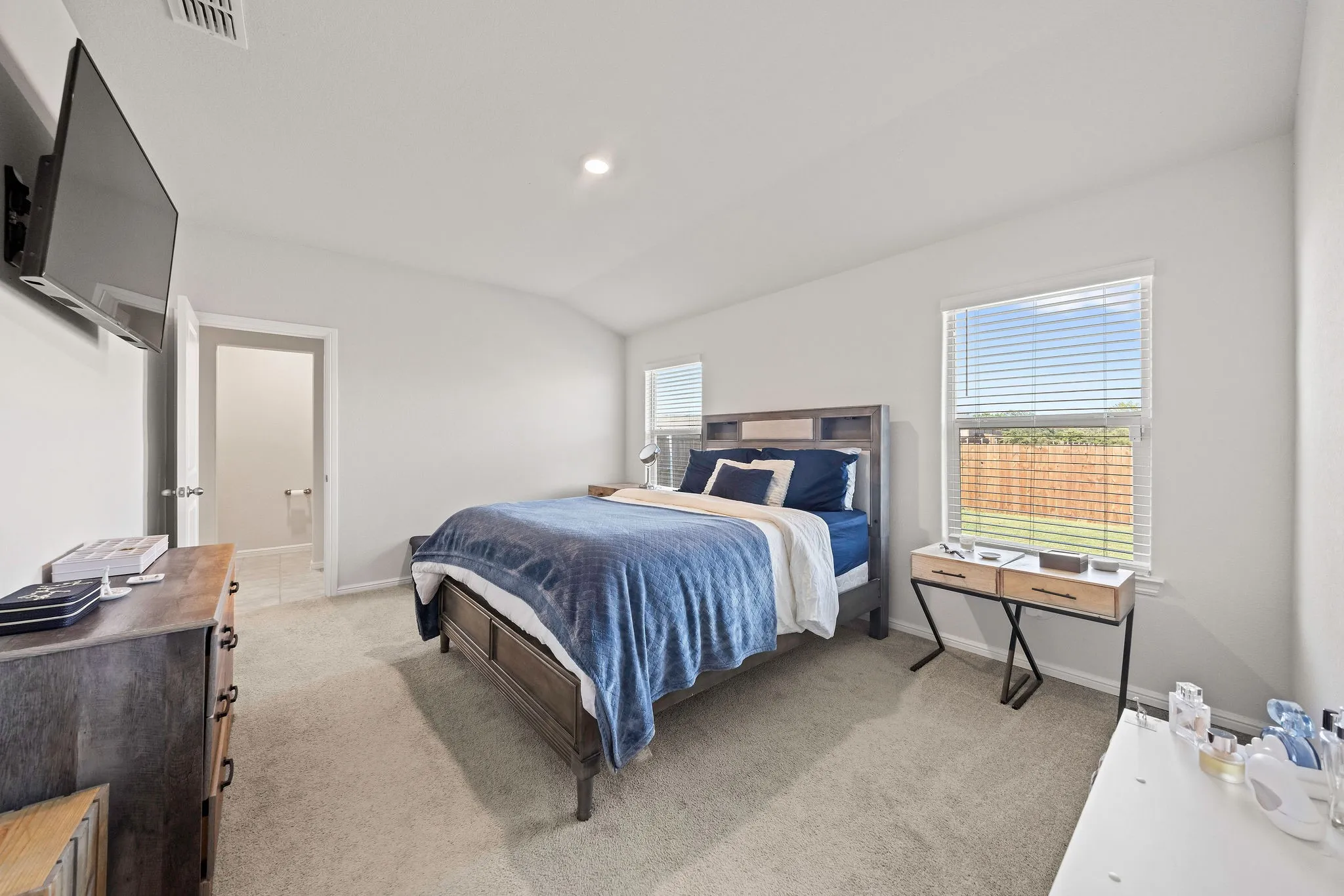 Bedroom with light carpet, lofted ceiling, and ensuite bath