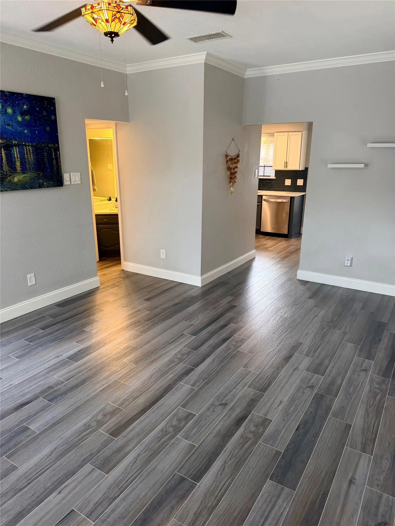 Wood-look tile flooring, crown molding, and a decorative ceiling fan with light fixture